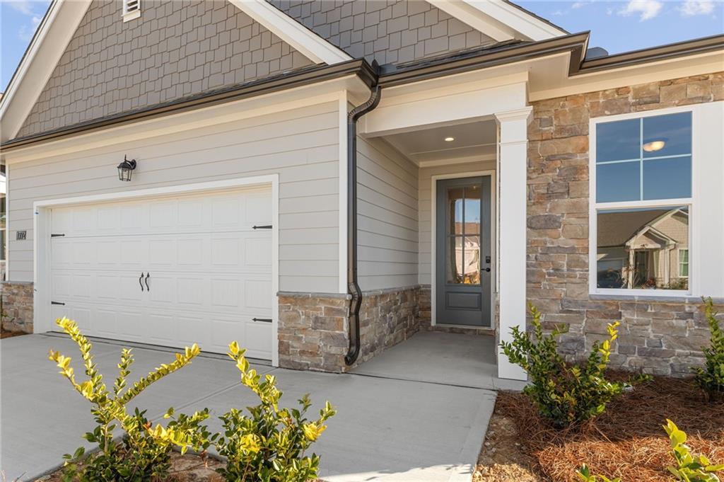 Front exterior of Davidson Homes The Glenwood A: single-story with 2-car garage, gray siding, stone accents, covered entry in Kelly Preserve, Loganville, GA