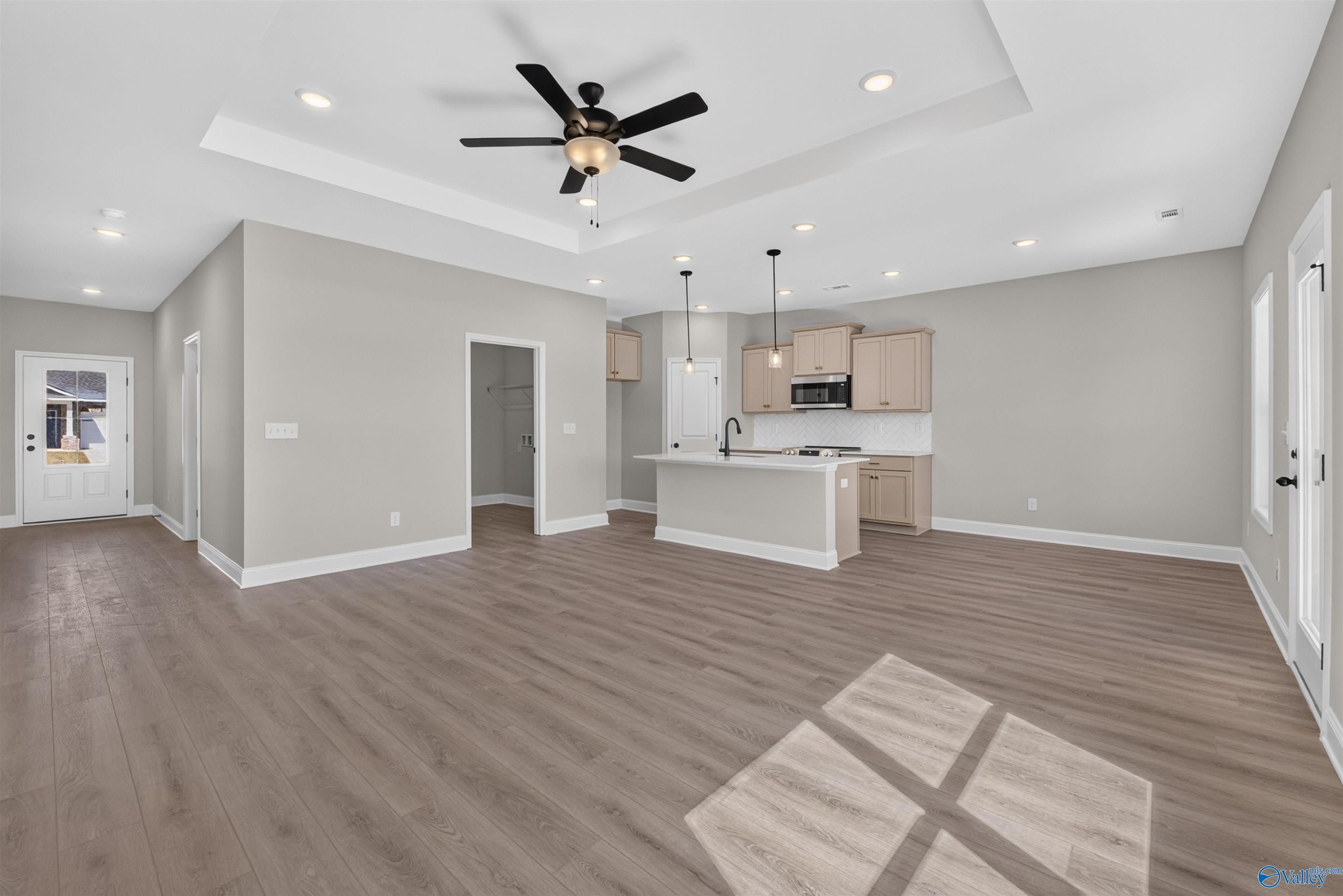 Open-concept living and kitchen with tray ceiling, island, and pendant lights in Davidson Homes The Butler plan, Hazel Green, AL