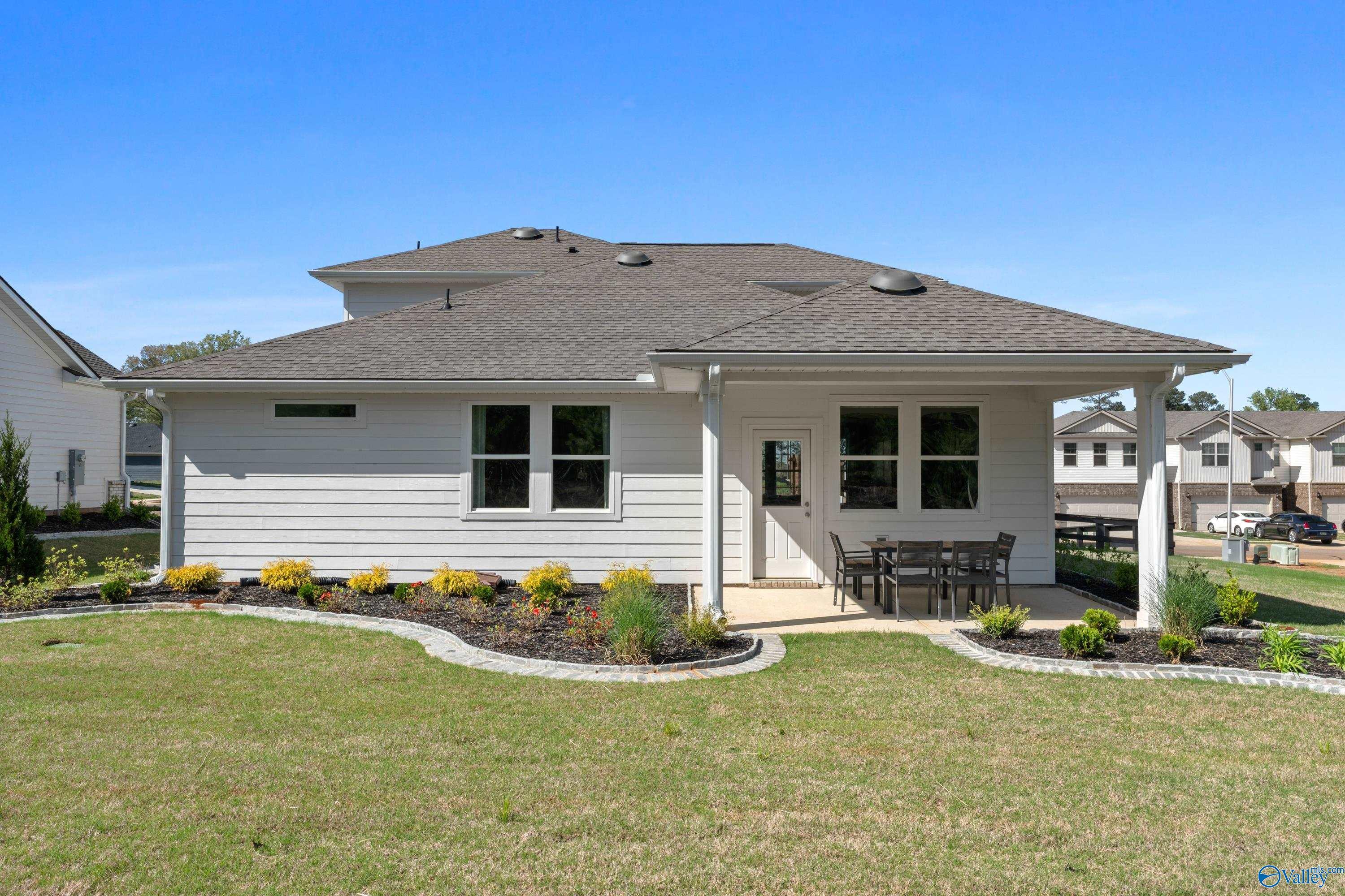 Side view of Davidson Homes The Stella two-story home with covered patio, outdoor seating, and landscaped yard in Evergreen Mill, Madison, Alabama