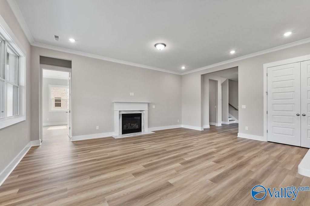 Cozy family room with gas fireplace, light hardwood floors, and neutral walls in Evermore Homes The Oxford, Owens Cross Roads, Alabama