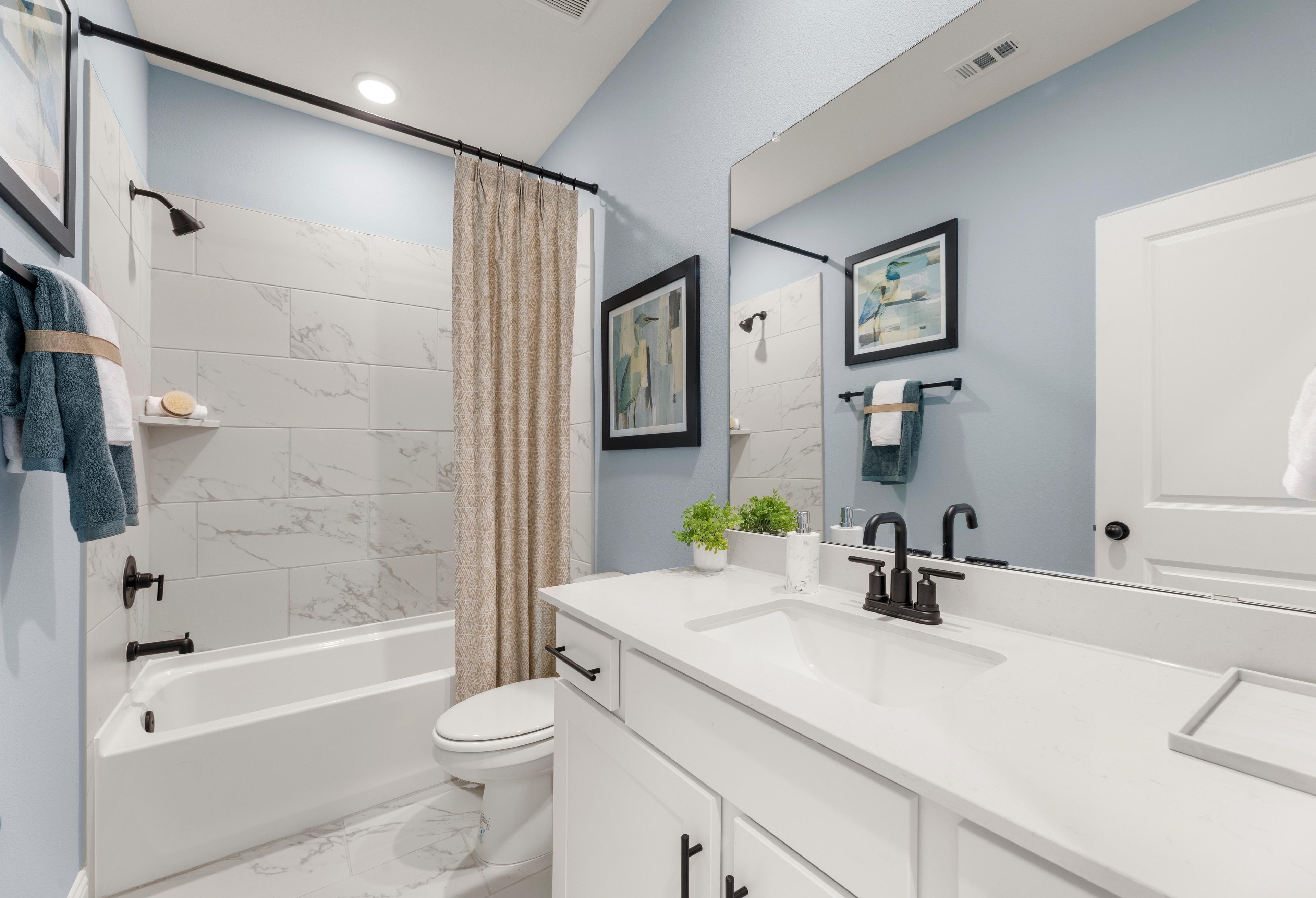 Spacious master bathroom in The Laurel G with subway tile shower, deep soaking tub, dual sink vanity, and soft blue walls