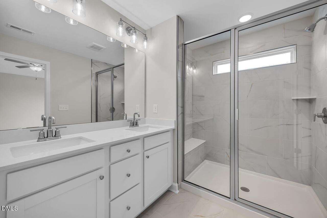 Elegant master bathroom with double vanity, frameless glass shower, marble tile bench in Davidson Homes The Avery, Knightdale, NC
