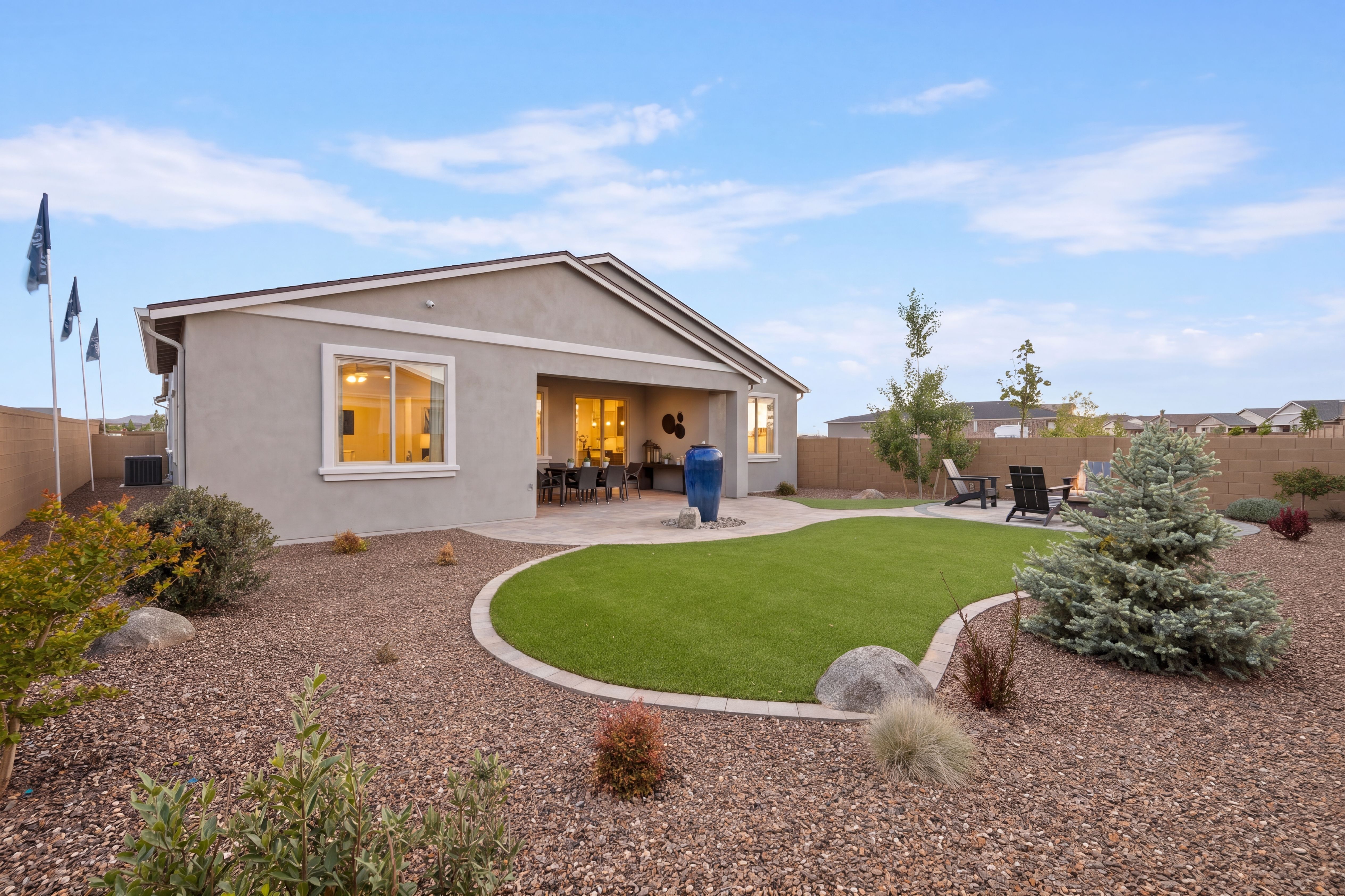 Desert backyard with curved turf lawn, covered patio, seating, and spruce trees at North Ridge in Pronghorn Ranch, Prescott Valley AZ
