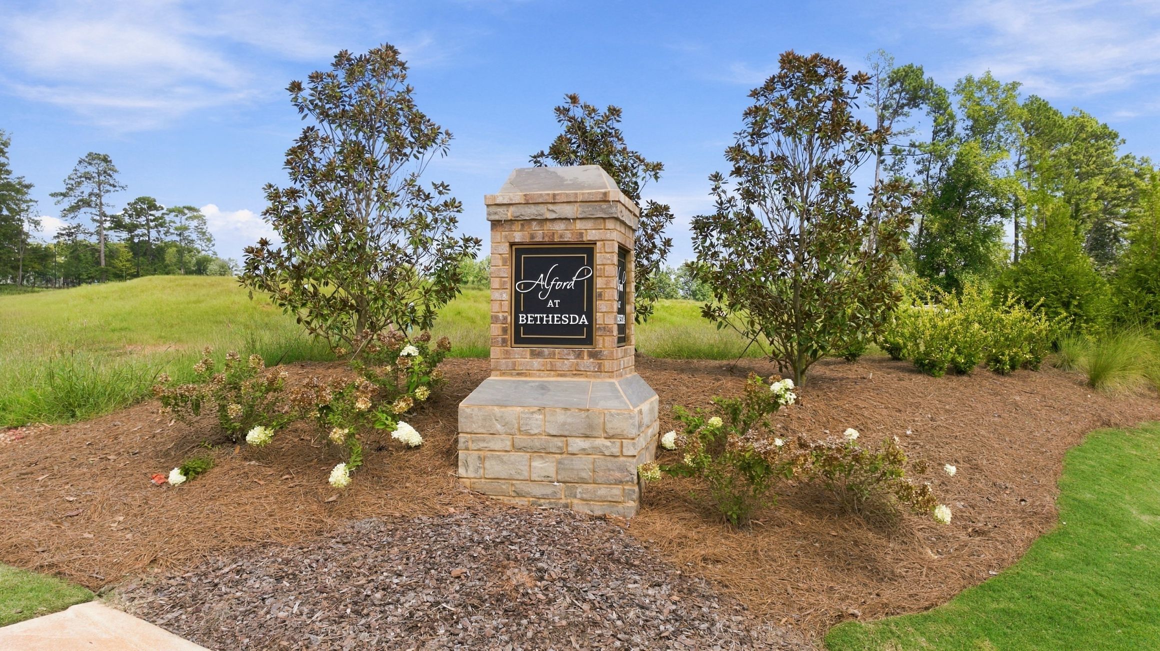 Brick and stone entrance monument at Alford at Bethesda in Lawrenceville, Georgia surrounded by landscaped shrubs and trees
