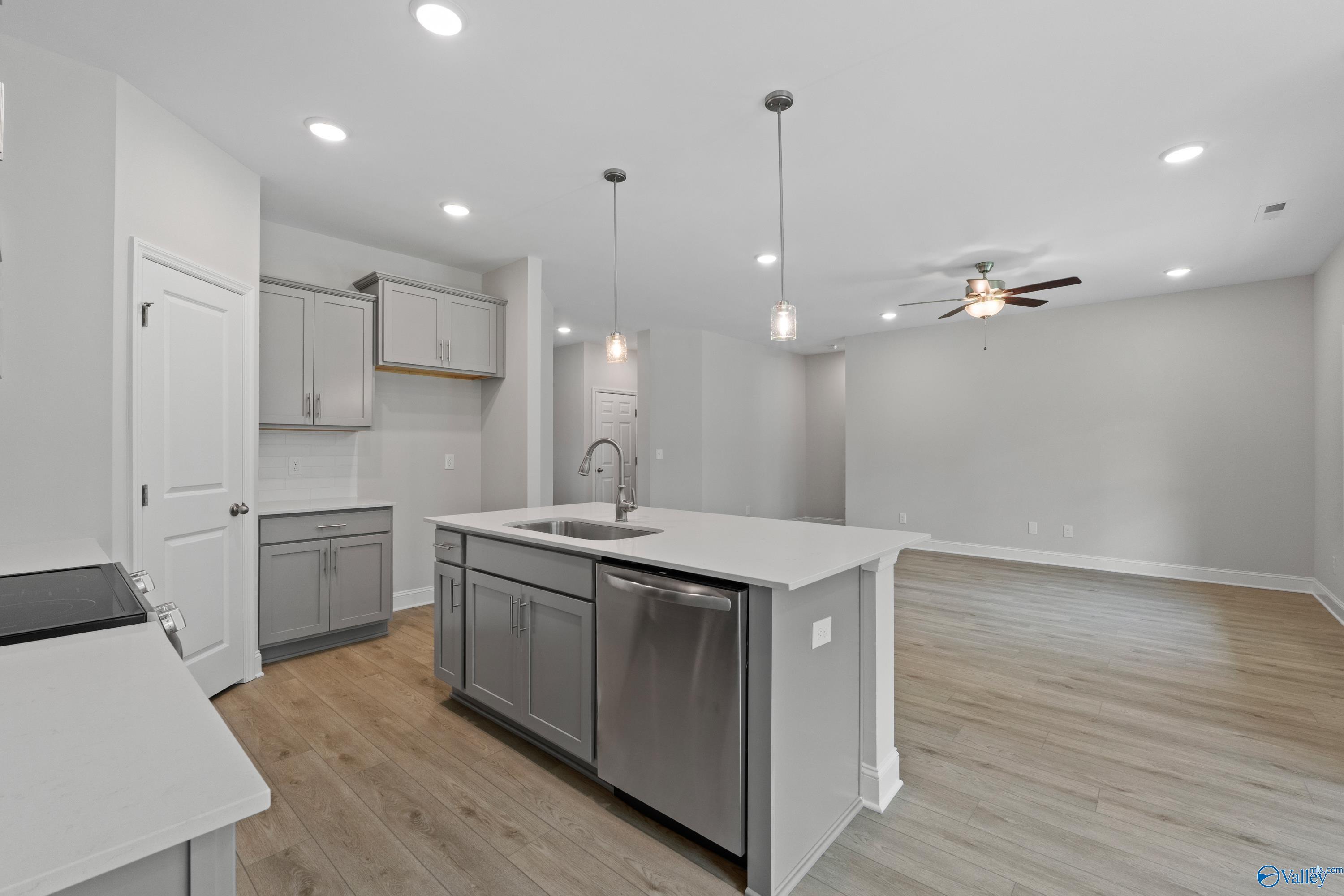 Modern open-concept kitchen with gray cabinets, white quartz island, stainless sink in The Asheville by Davidson Homes, Huntsville AL