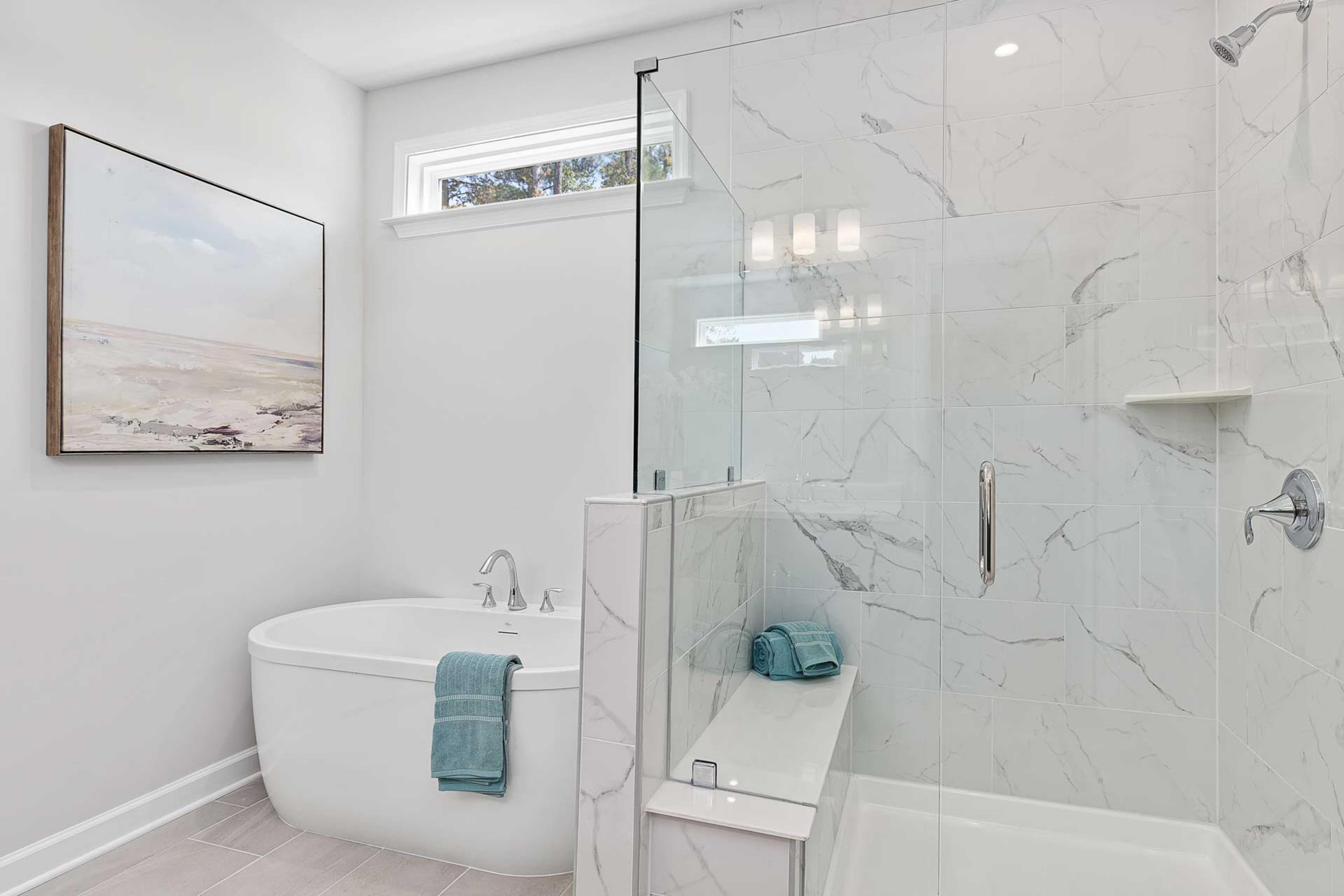 Luxury spa bathroom in Glenmere Knightdale NC by Davidson Homes with freestanding tub, glass shower, and marble tiles