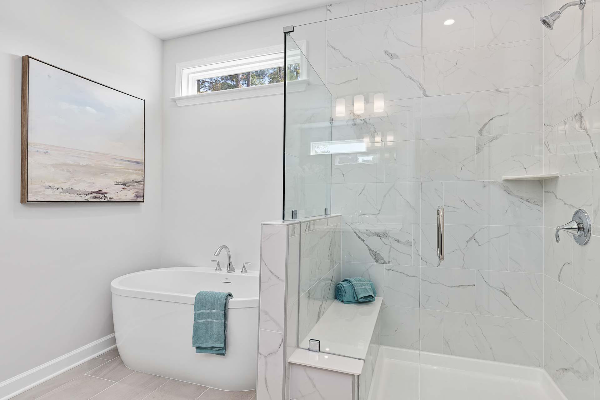 Luxury spa bathroom in Glenmere Knightdale NC by Davidson Homes with freestanding tub, glass shower, and marble tiles