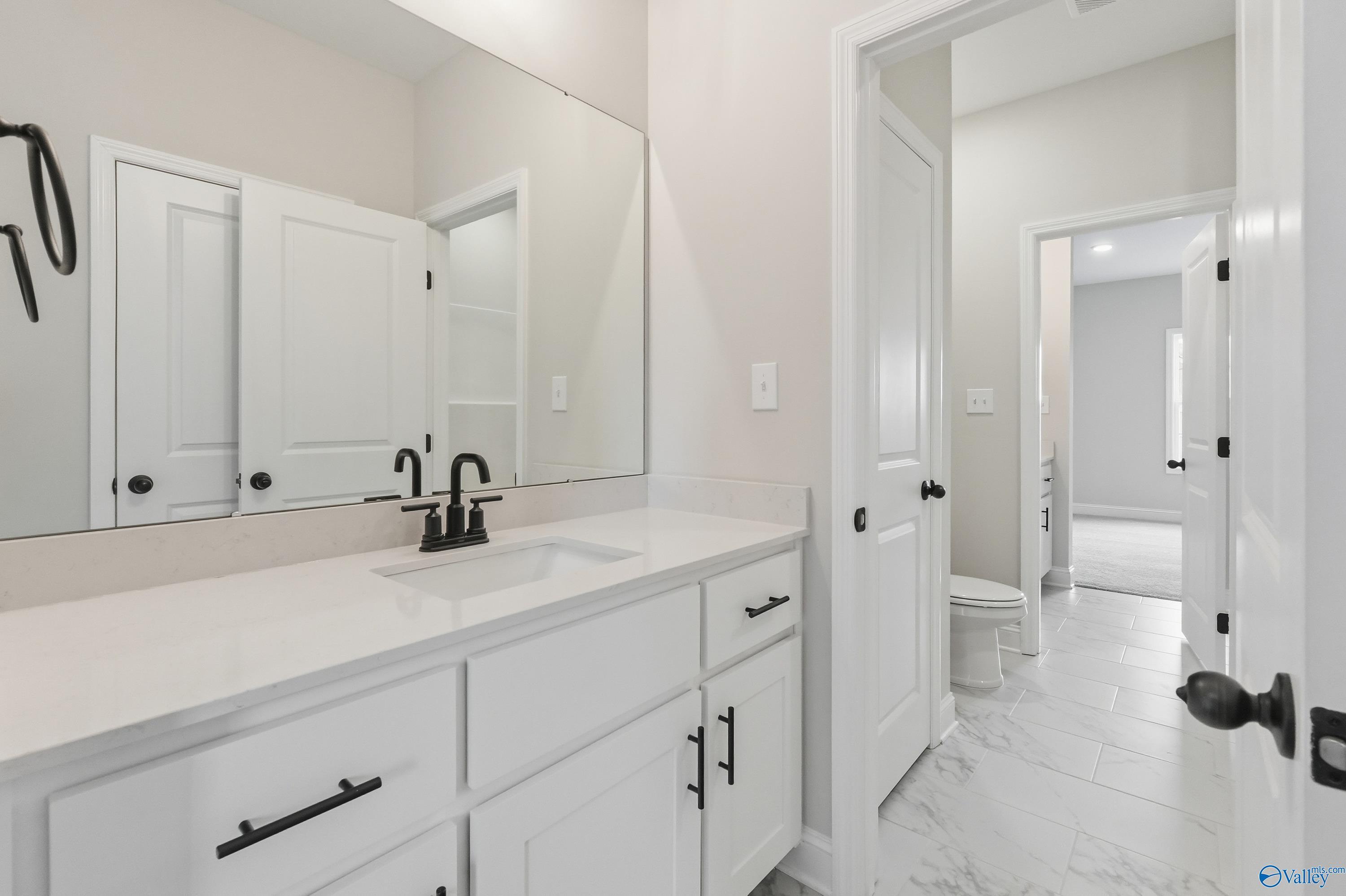 Elegant master bathroom with white shaker vanity, quartz countertop, chrome faucet, and frameless mirror in Davidson Homes The Finleigh, Meridianville, Alabama