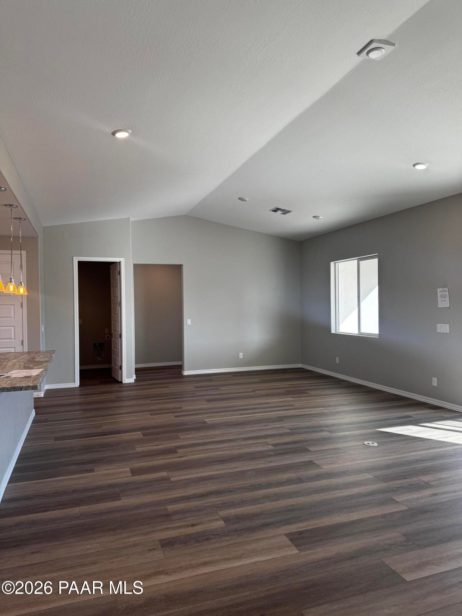 Spacious open living area with vaulted ceilings, gray walls, wood floors, and large windows in 3-bedroom Davidson Homes The Daybreak B, Prescott AZ