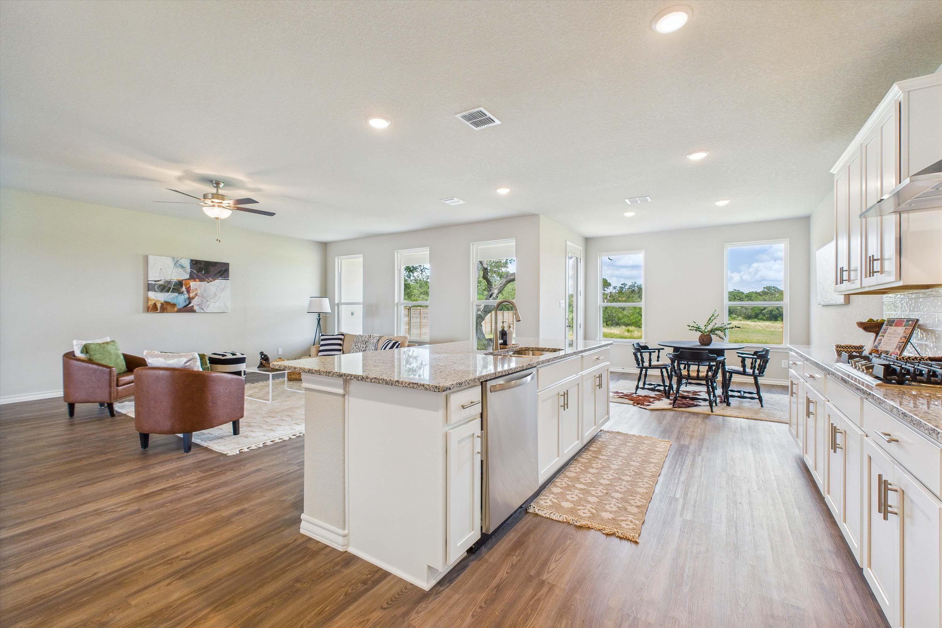 Open-concept kitchen and living area in The Foster featuring a large island, granite countertops, and modern finishes.