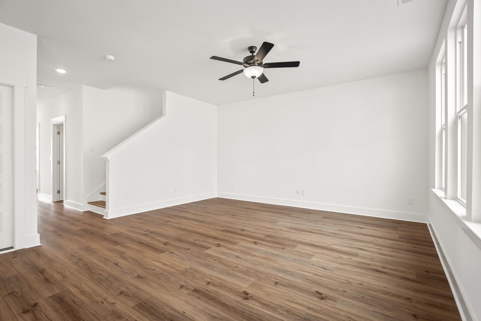 Bright entry foyer with hardwood floors, ceiling fan, staircase, and large windows in Davidson Homes The Logan C, Gallatin, TN
