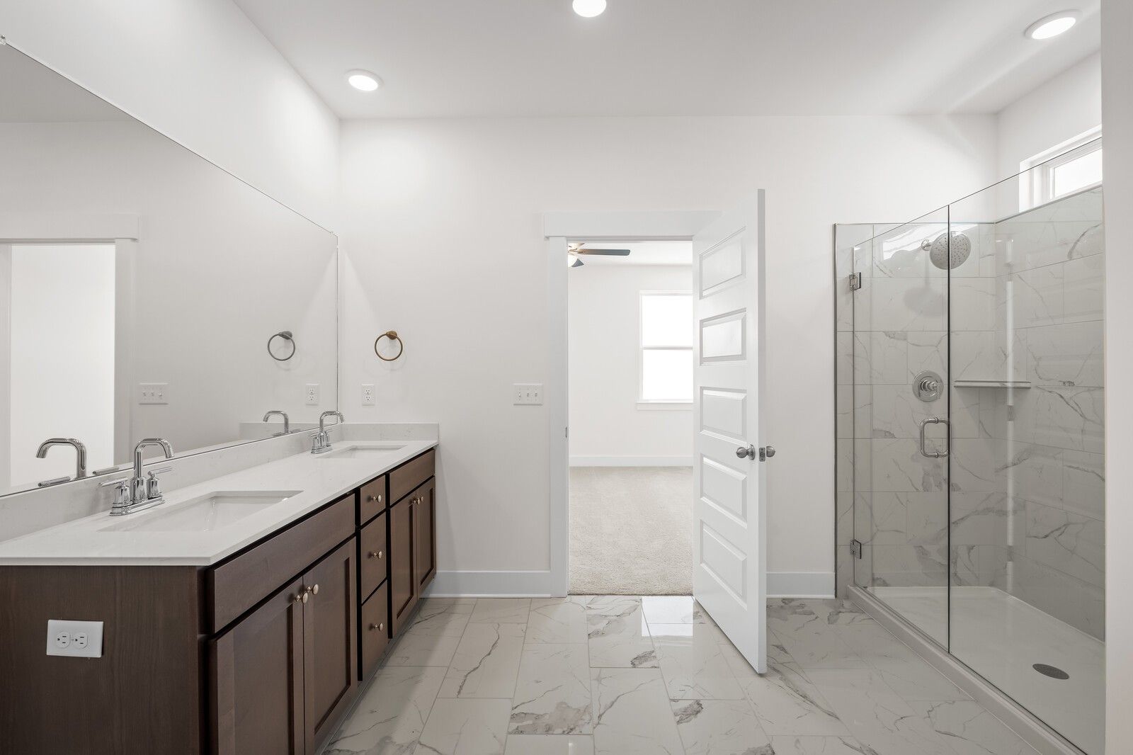 Modern primary bathroom with dual vanity and walk-in glass shower in The Cottonwood E plan at Woods Crossing, Gallatin, TN.