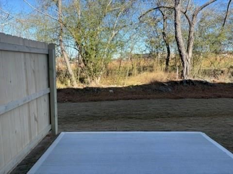 Private backyard with concrete patio slab, wooden fence, and mature trees in Davidson Homes Marion A, Lake Shore, Winder, GA