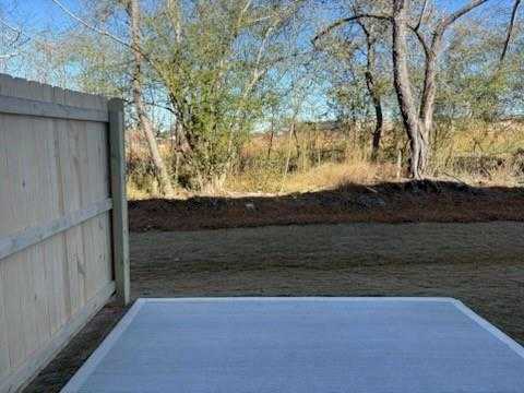 Private backyard with concrete patio slab, wooden fence, and mature trees in Davidson Homes Marion A, Lake Shore, Winder, GA