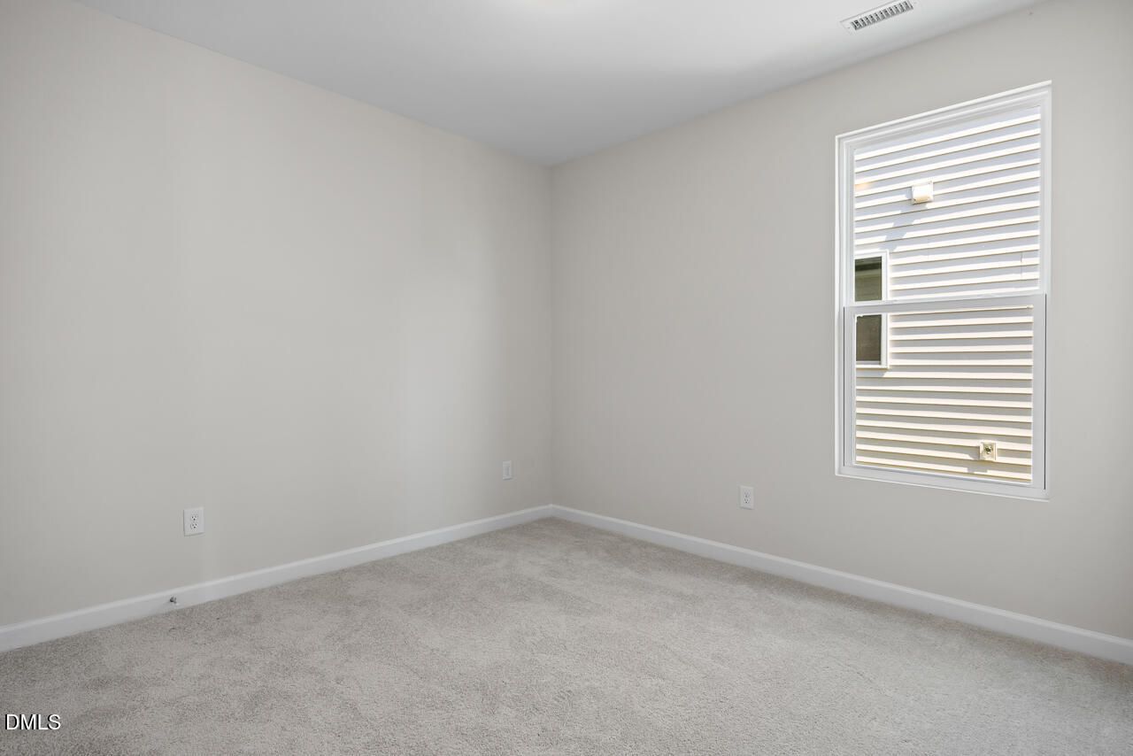 Bright empty bedroom with plush carpet and white walls in Davidson Homes The Daphne D plan at Woodland Crossing, Zebulon NC
