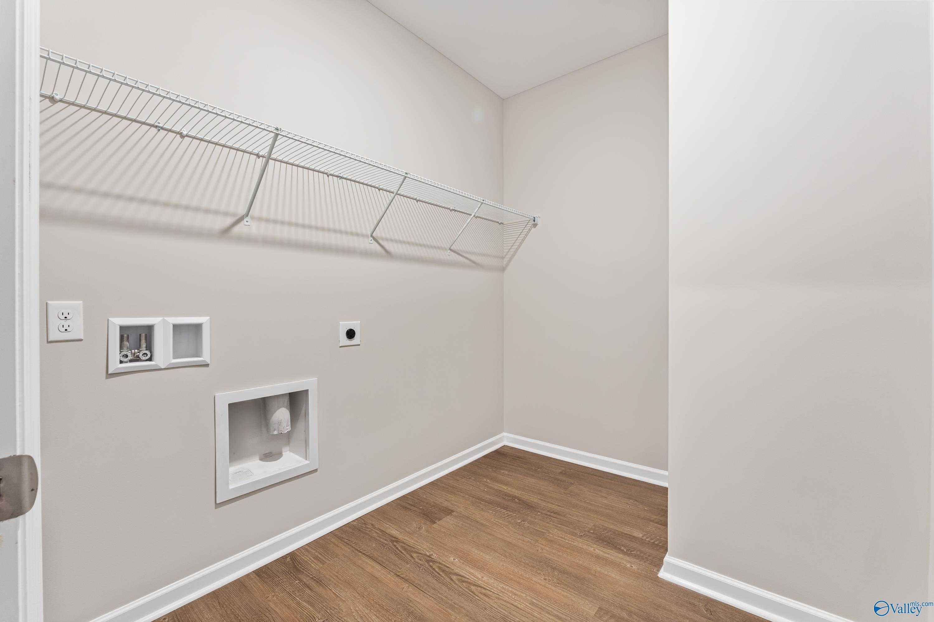 Bright laundry room with wire shelving, washer-dryer hookups, and hardwood floors in Davidson Homes The Phoenix, Fayetteville, TN