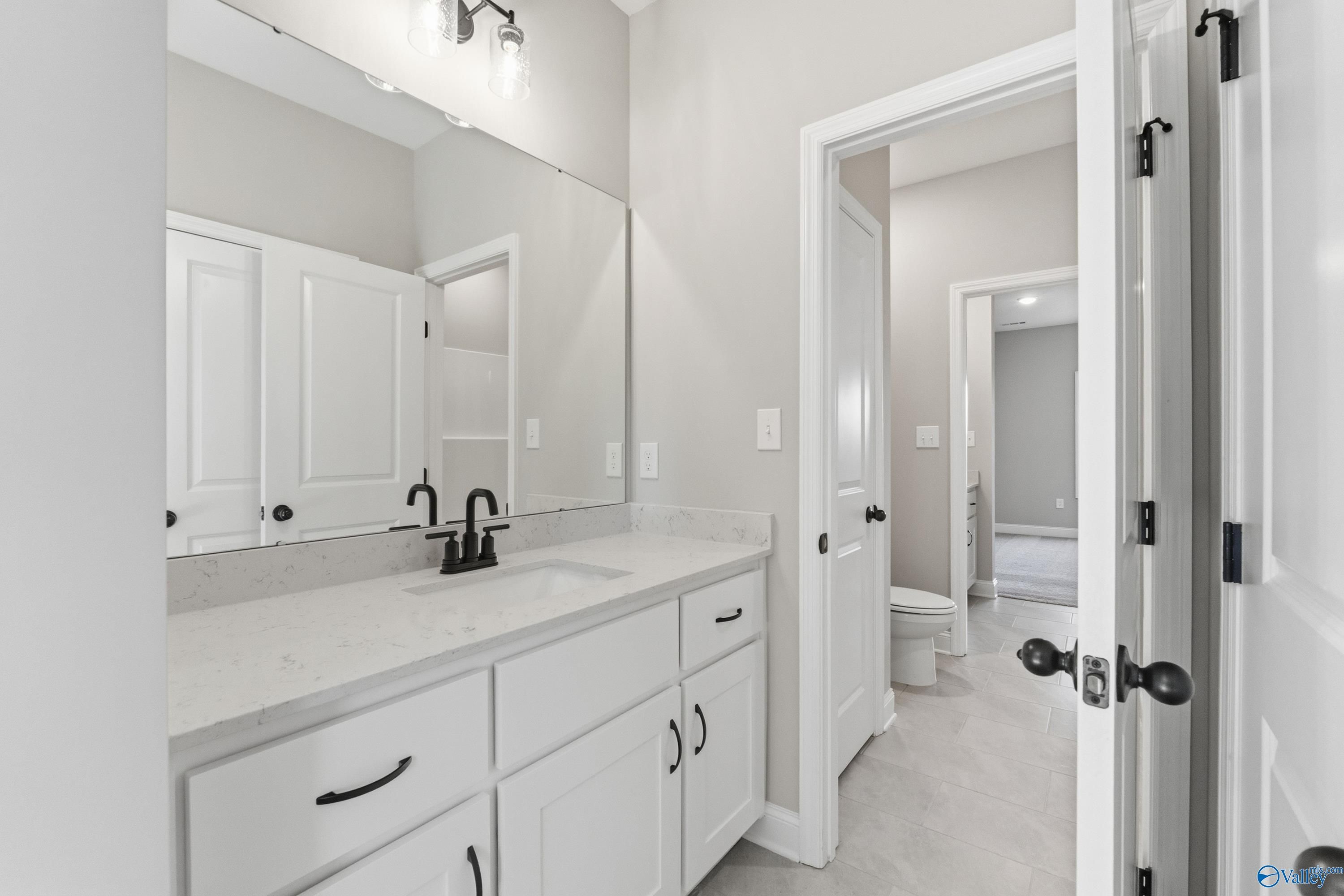 Elegant master bathroom with white quartz vanity, black faucet, and large mirror in Davidson Homes The Finleigh, Meridianville, Alabama