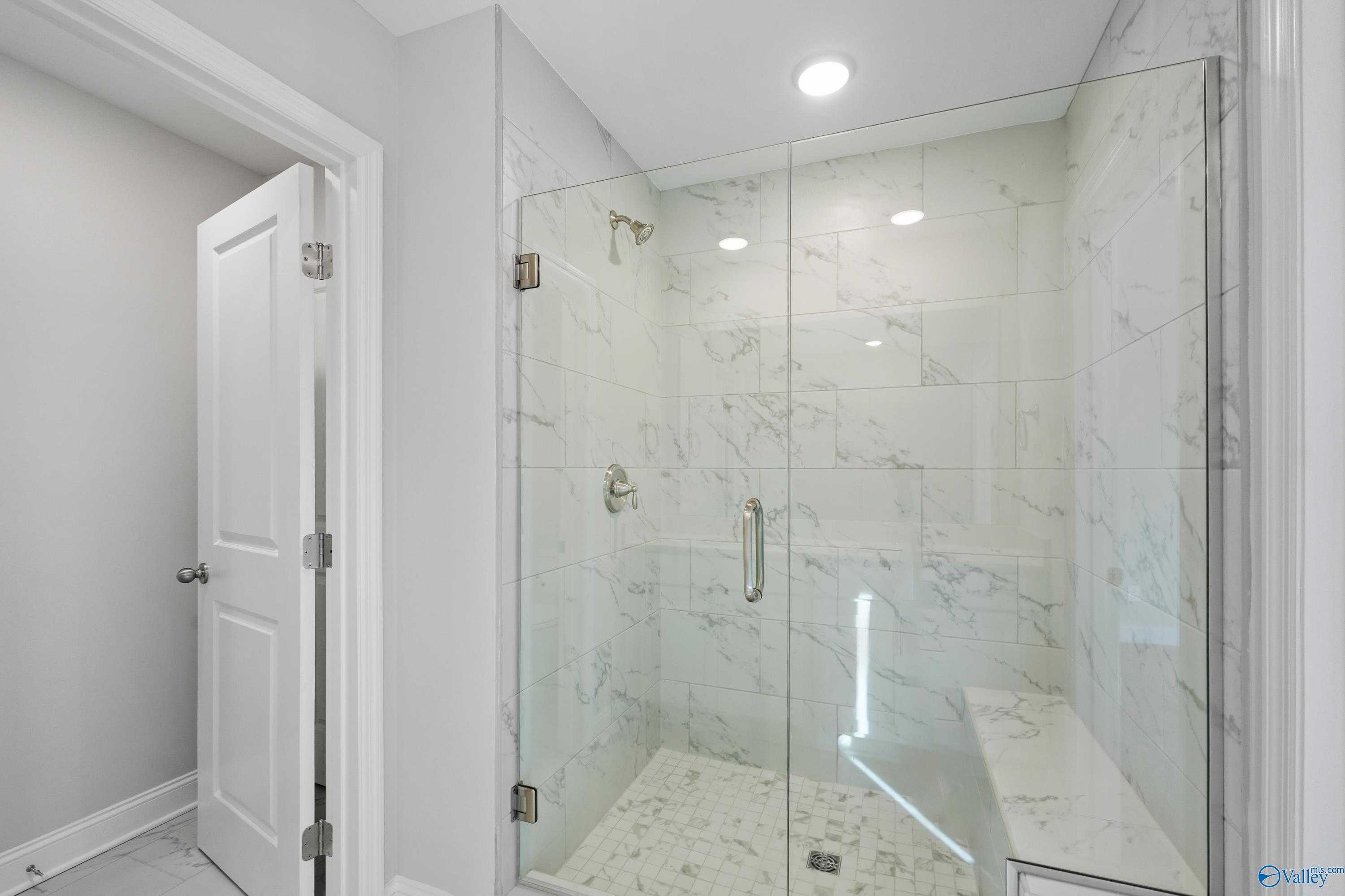 Elegant frameless glass shower with white subway tile, bench seat in master bath of Davidson Homes The Camden, Huntsville AL