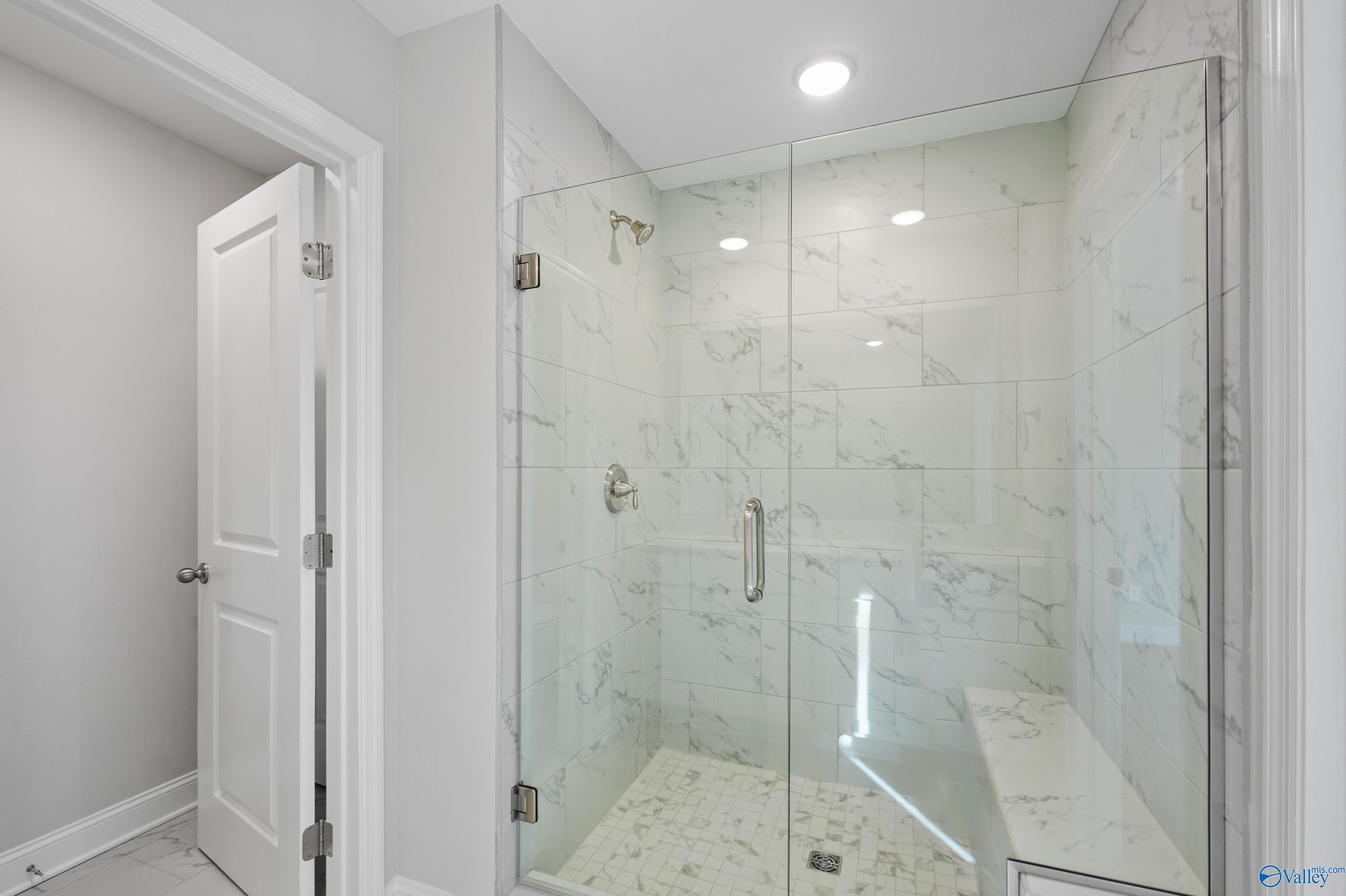 Modern frameless glass shower with white marble tiles and built-in bench in master bath, Davidson Homes The Camden, Huntsville AL