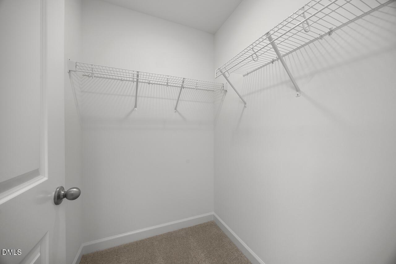 Walk-in closet with white wire shelving in The Adalynn A floor plan at Gregory Village in Lillington, North Carolina.