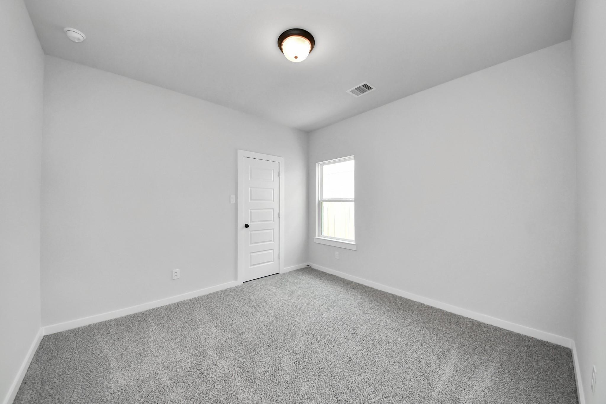 Spacious secondary bedroom with neutral carpet in The Everett C floor plan at River Ranch Meadows, Dayton, Texas.