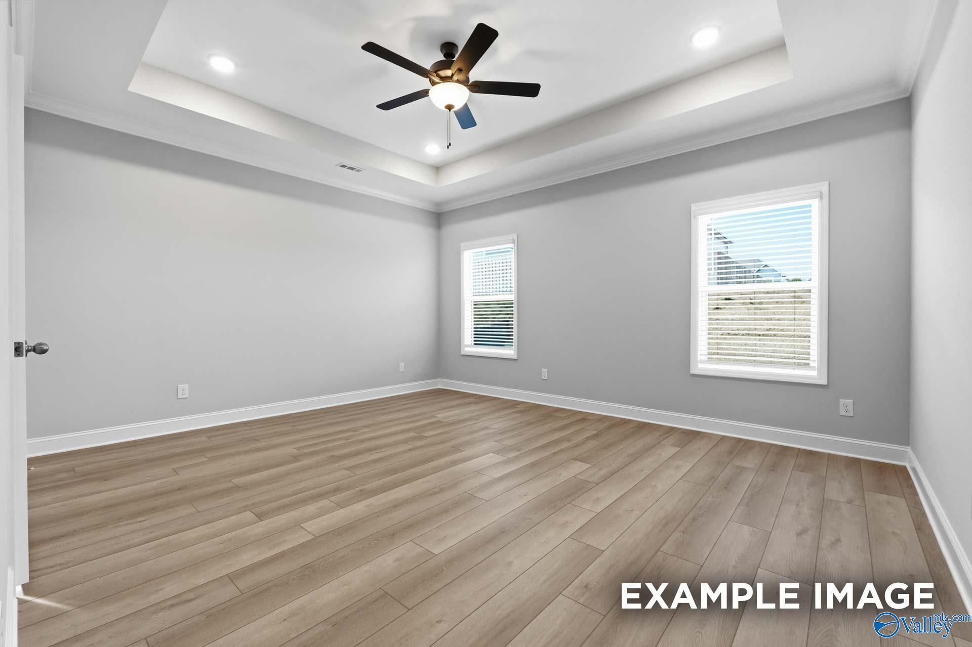 Bright bedroom with tray ceiling, ceiling fan, and luxury vinyl plank flooring in Davidson Homes The Harrison D, Hazel Green, AL