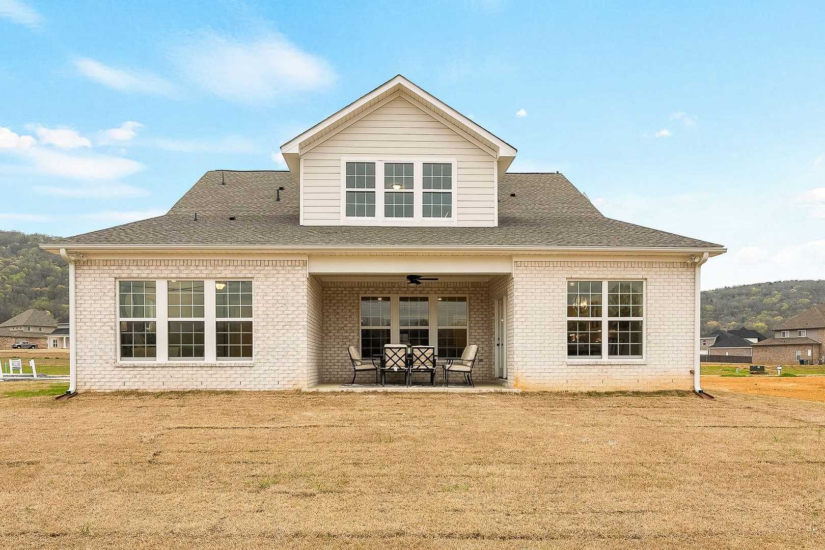 Rear elevation of The Oxford 2-story home featuring covered porch, white siding, patio seating, and scenic yard in Owens Cross Roads
