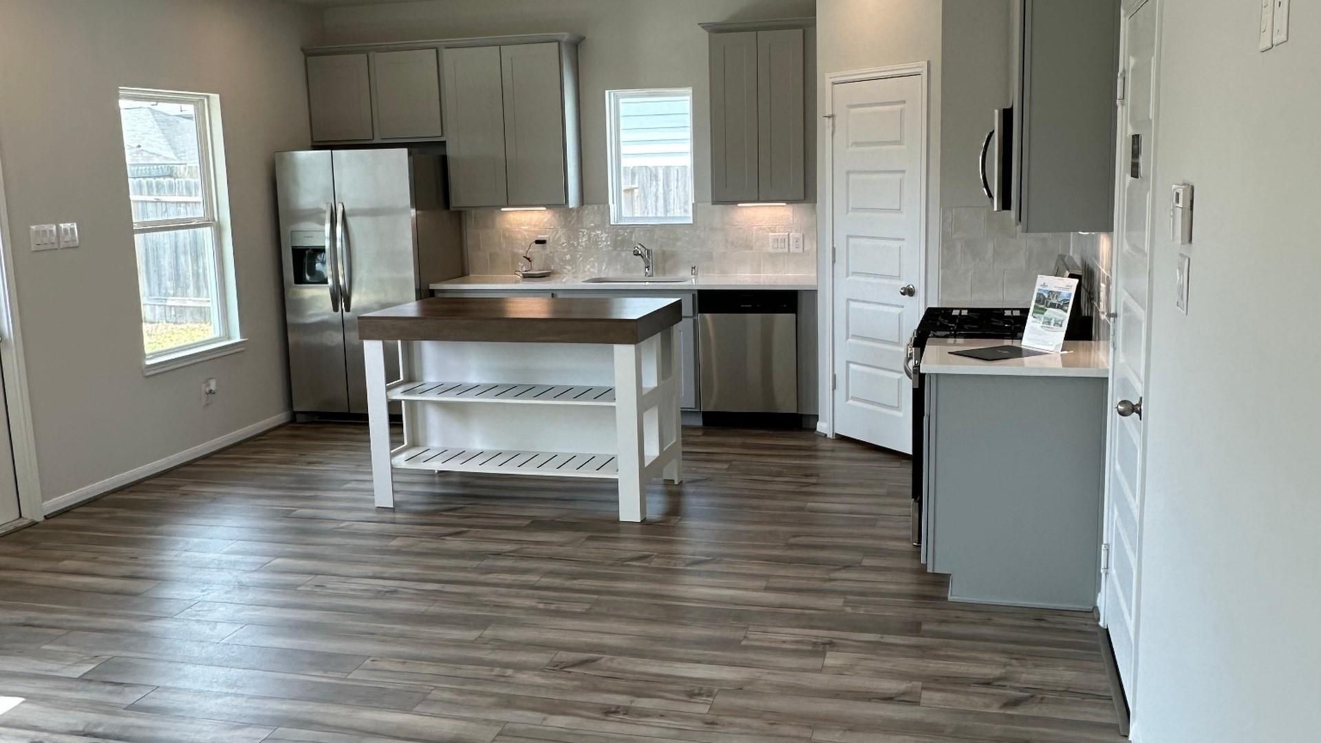 Modern kitchen with gray cabinets, stainless appliances, and island in Davidson Homes Trinity F floor plan, Splendora, Texas