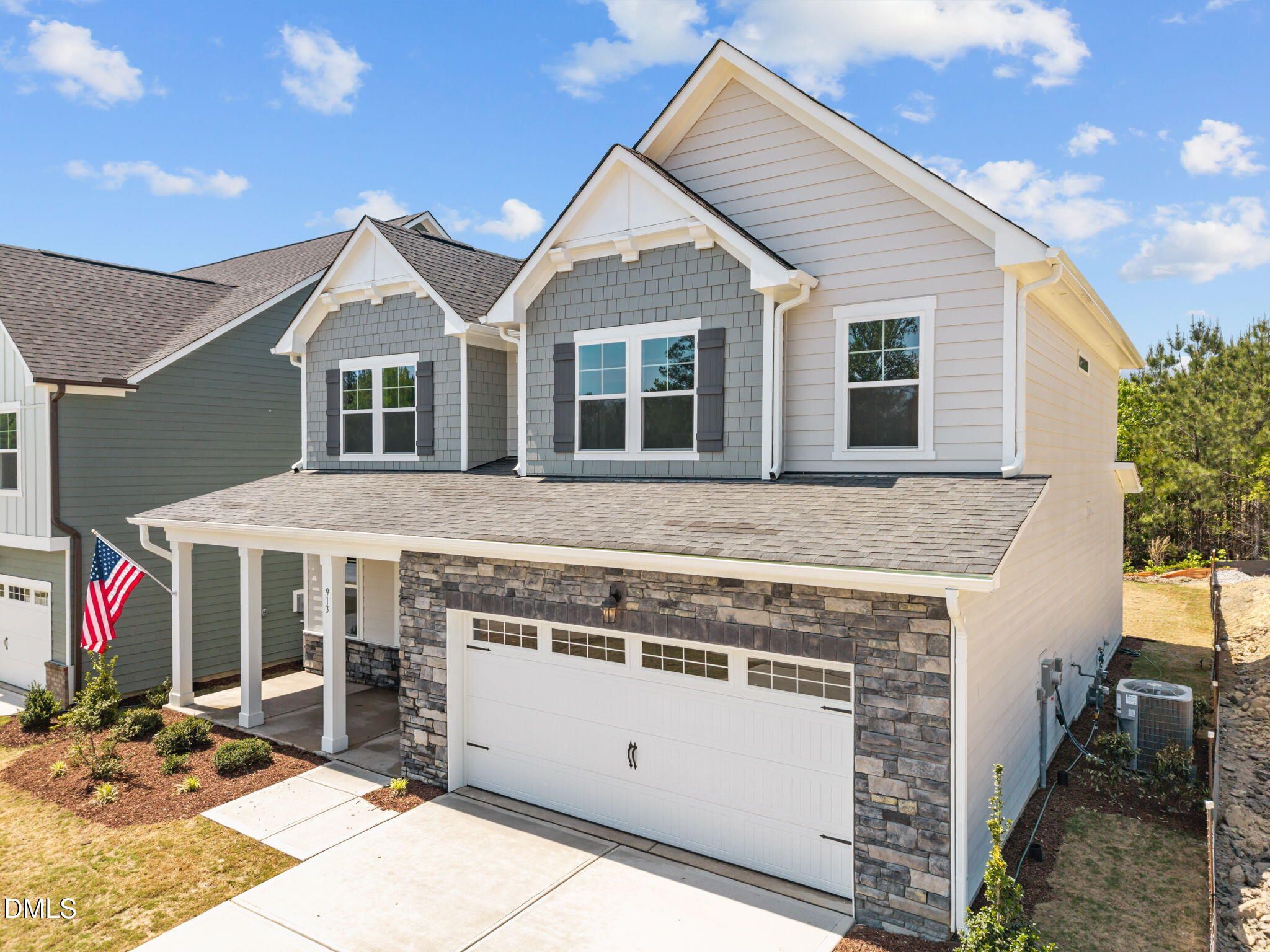Modern two-story home exterior with gray siding, stone-accented two-car garage, and covered porch in Wendell Ridge, North Carolina