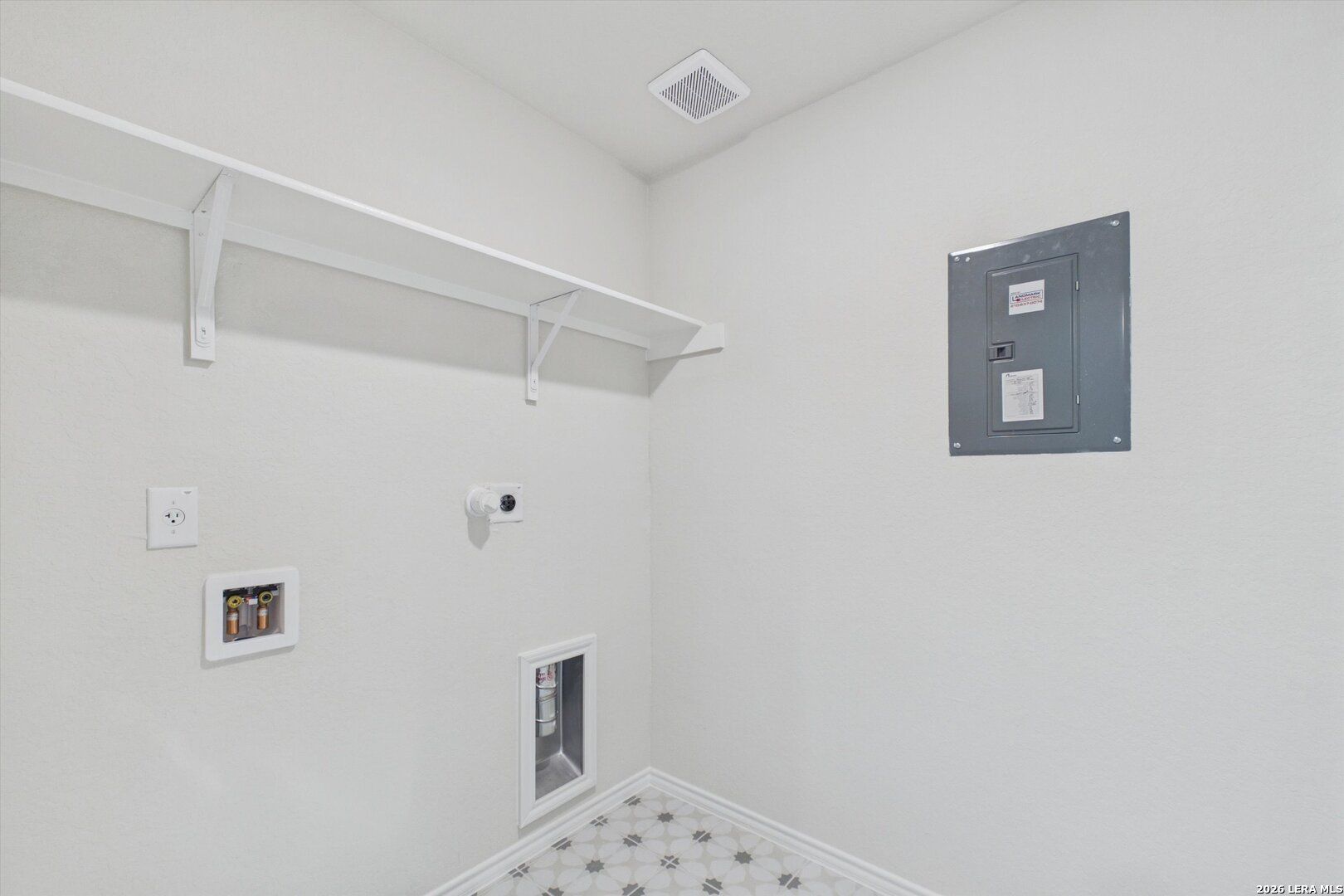 Laundry room with storage shelving and utility connections in The Charlotte B floor plan at Meadows at Oak Creek.