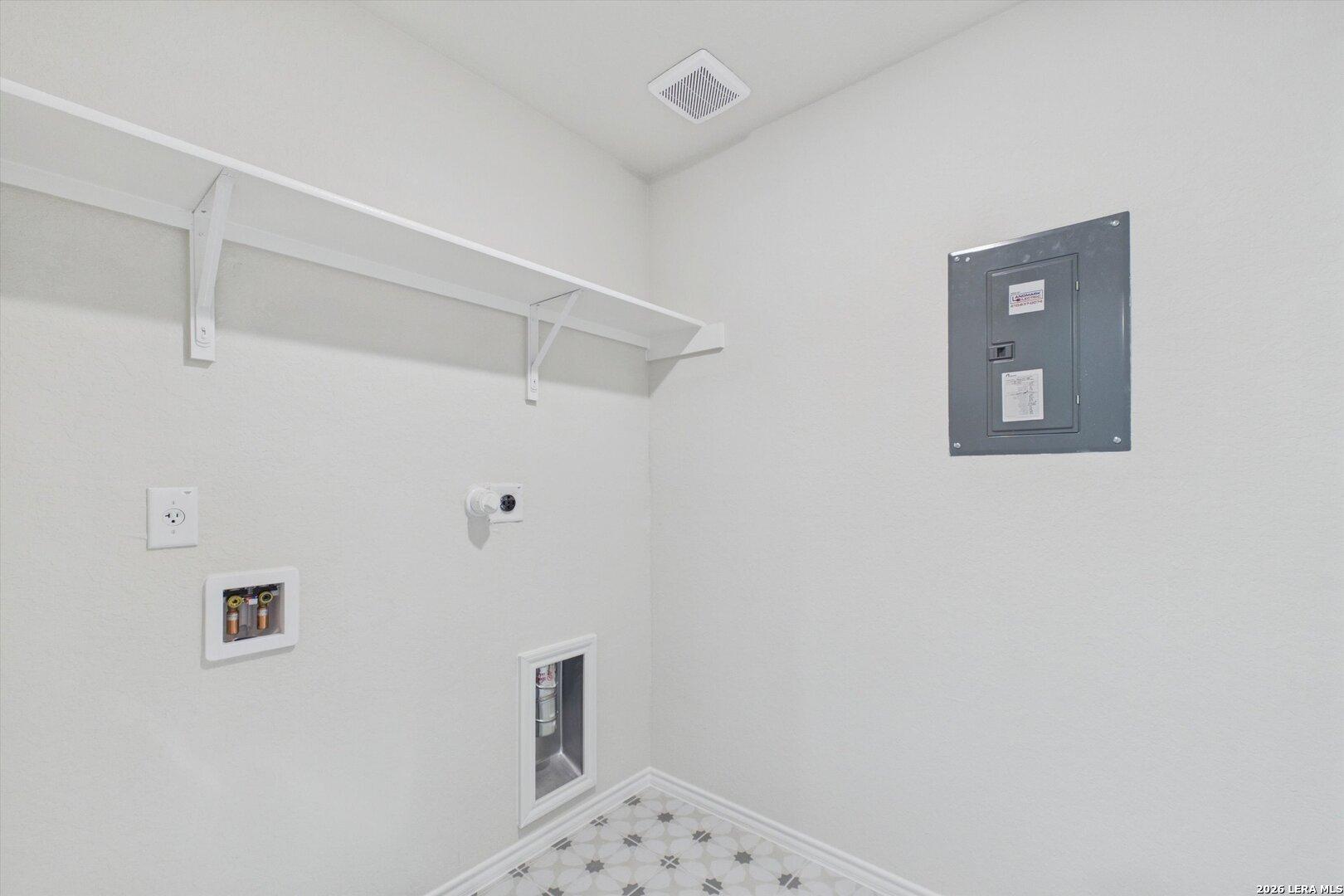 Laundry room with storage shelving and utility connections in The Charlotte B floor plan at Meadows at Oak Creek.