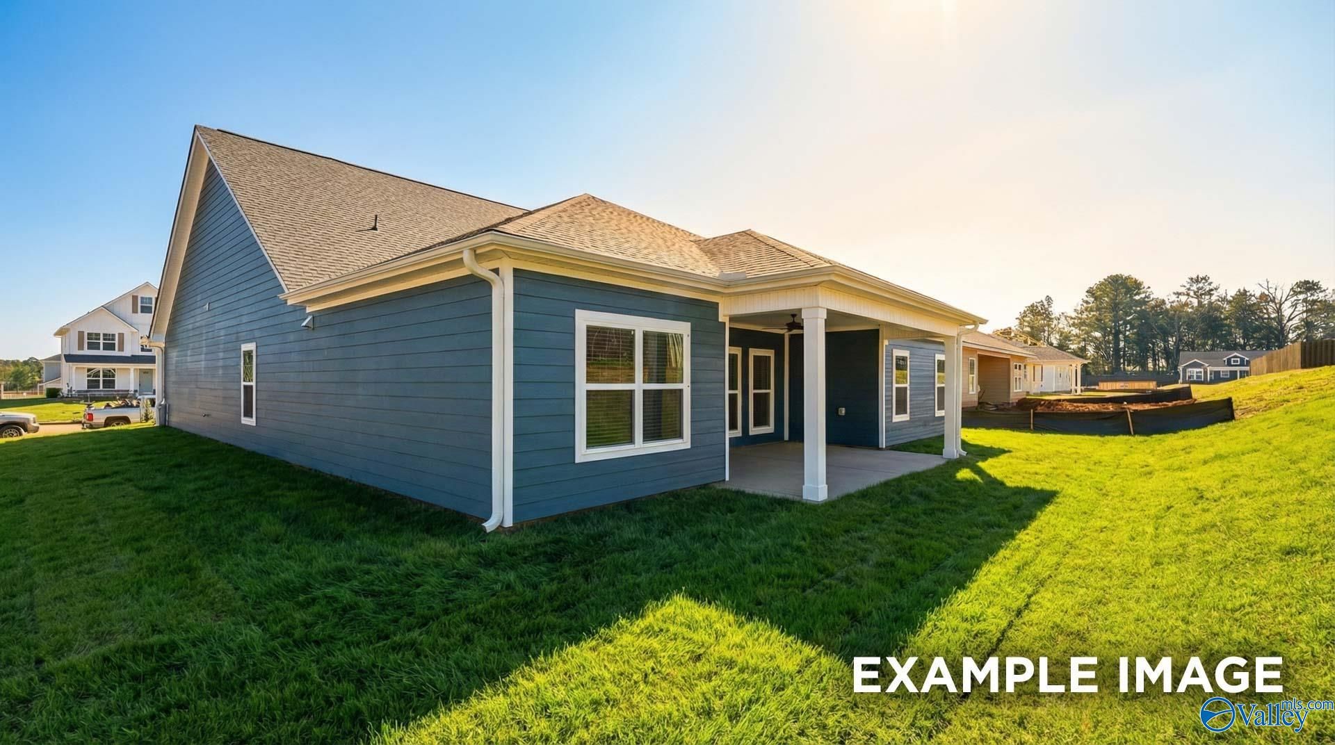 Blue two-story home with covered side patio, lush green lawn, and backyard garden in Anderson Farm, Athens, Alabama - Davidson Homes Harrison C