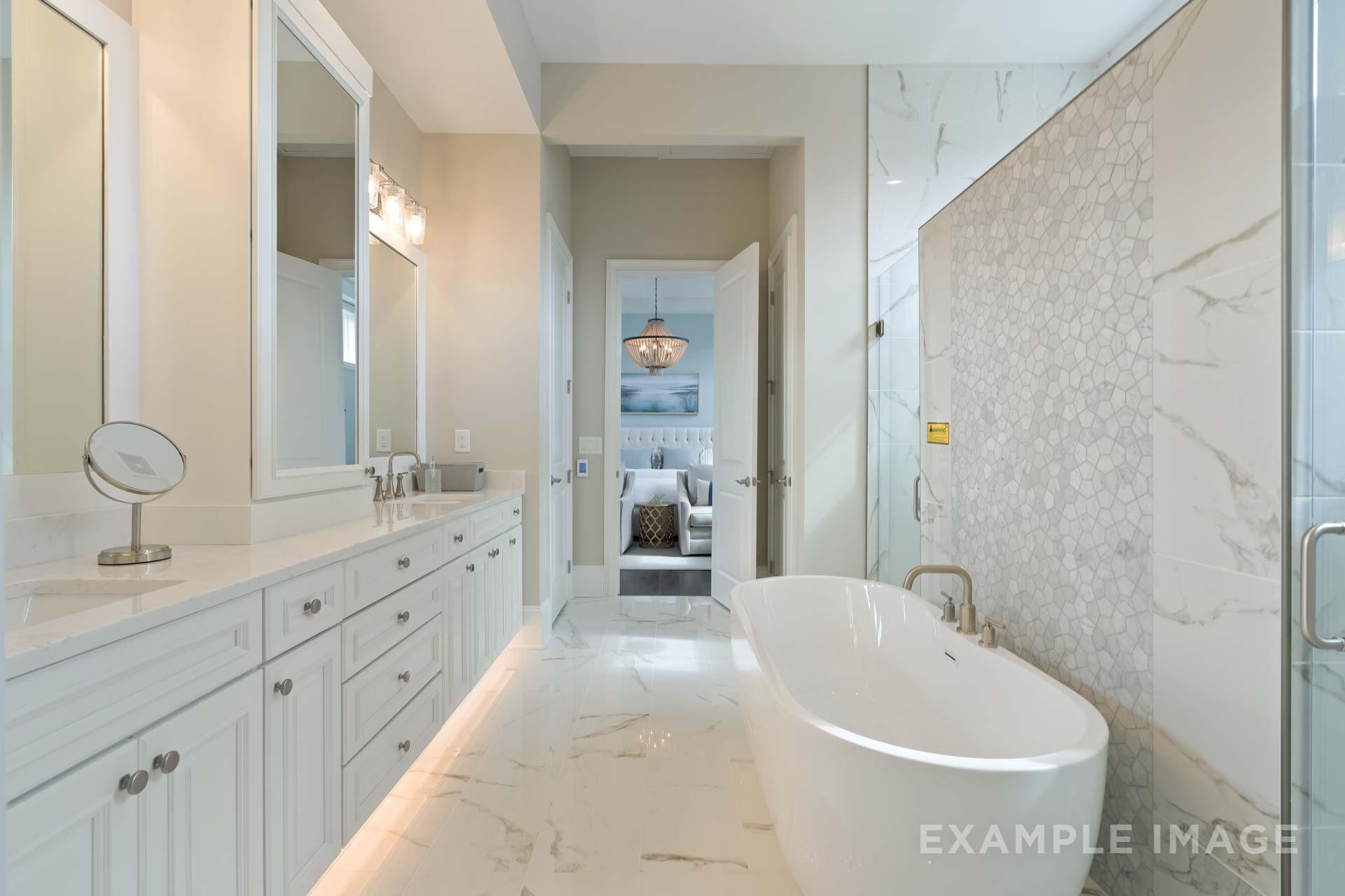 Spacious master bathroom in The Seaside home design featuring freestanding tub, double vanity, and marble-tiled shower