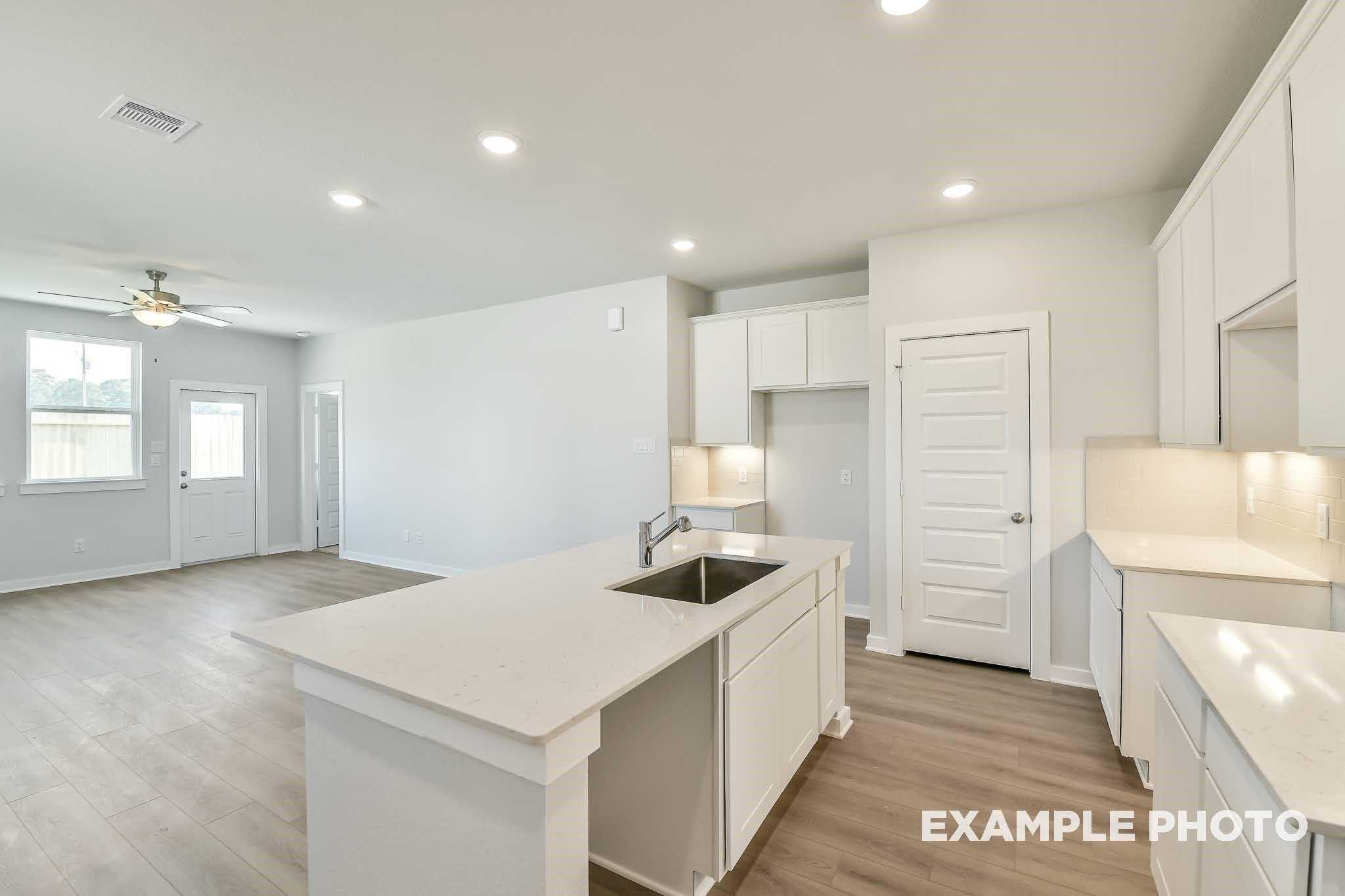 Bright open-concept kitchen with white quartz island, sink, and cabinets in Davidson Homes The Colorado F, Conroe, Texas