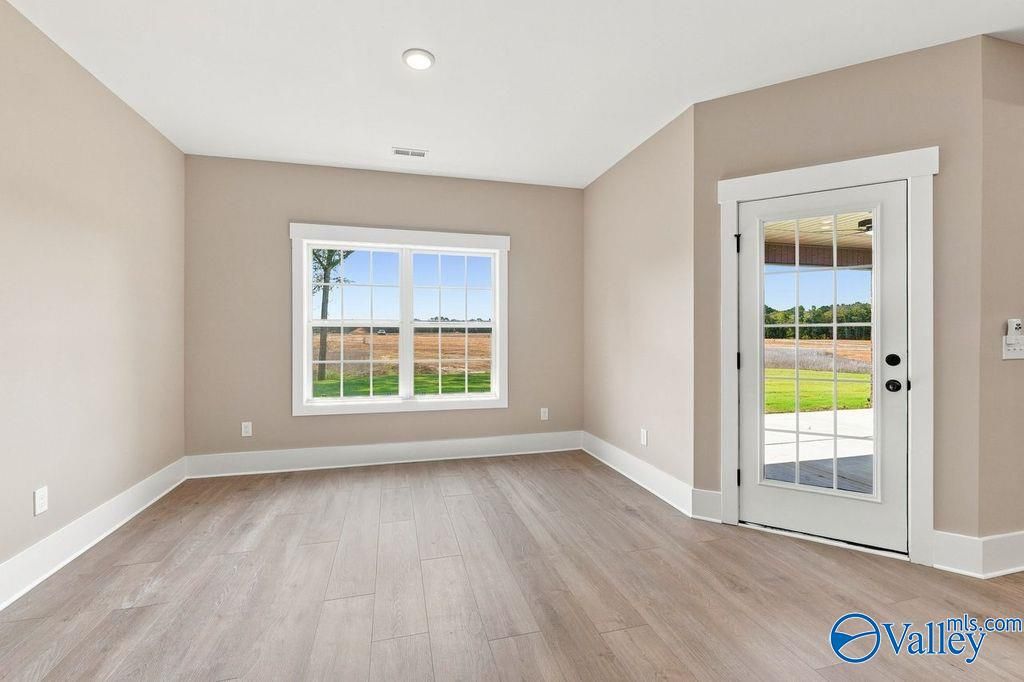 Bright sunroom with wood-style flooring and glass door access to backyard in The Rockford floor plan, Cain Park, Hartselle.