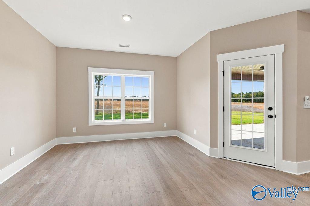 Bright sunroom with wood-style flooring and glass door access to backyard in The Rockford floor plan, Cain Park, Hartselle.
