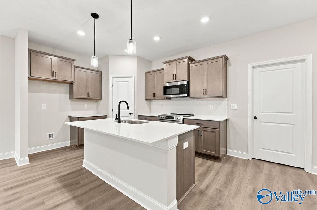 Modern kitchen with white island, gray cabinets, and stainless appliances in The Camilla C home at The Retreat at Cain Park.