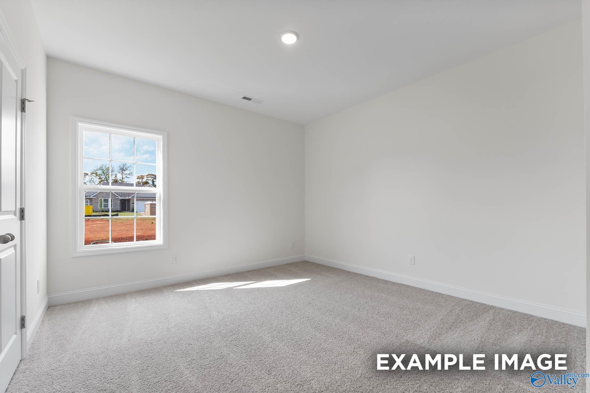 Bright, carpeted bedroom with neutral walls in The Harrison floor plan by Davidson Homes in River Road Estates, Decatur.