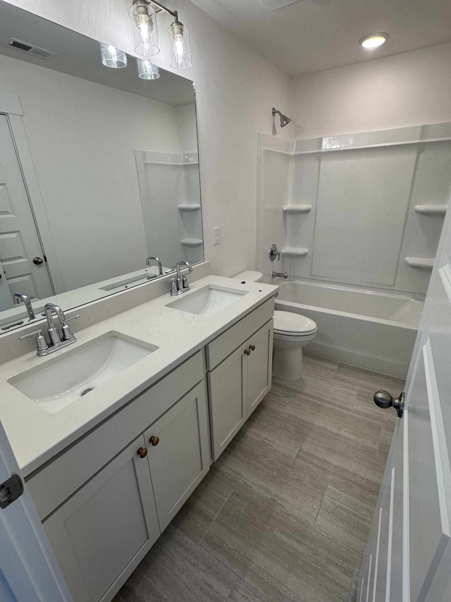 Modern bathroom with double vanity sinks, white quartz counters, and tub-shower combo in Davidson Homes The Ridgeport, Gallatin, TN