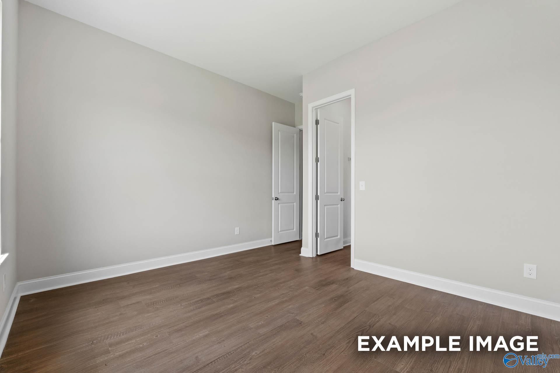 Spacious empty bedroom with hardwood floors and neutral walls in Evermore Homes The Arcadia, Owens Cross Roads, Alabama