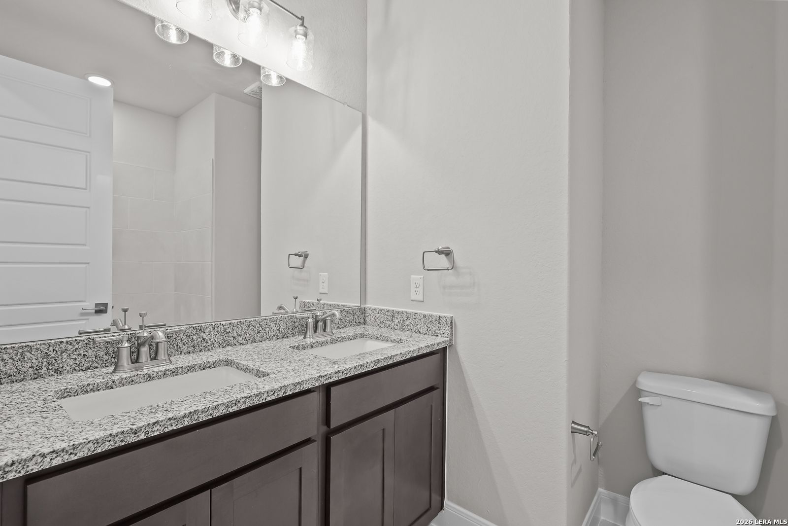 Modern master bathroom featuring double granite vanity, mirrors, and toilet in Davidson Homes The Rockford G, Ladera, San Antonio