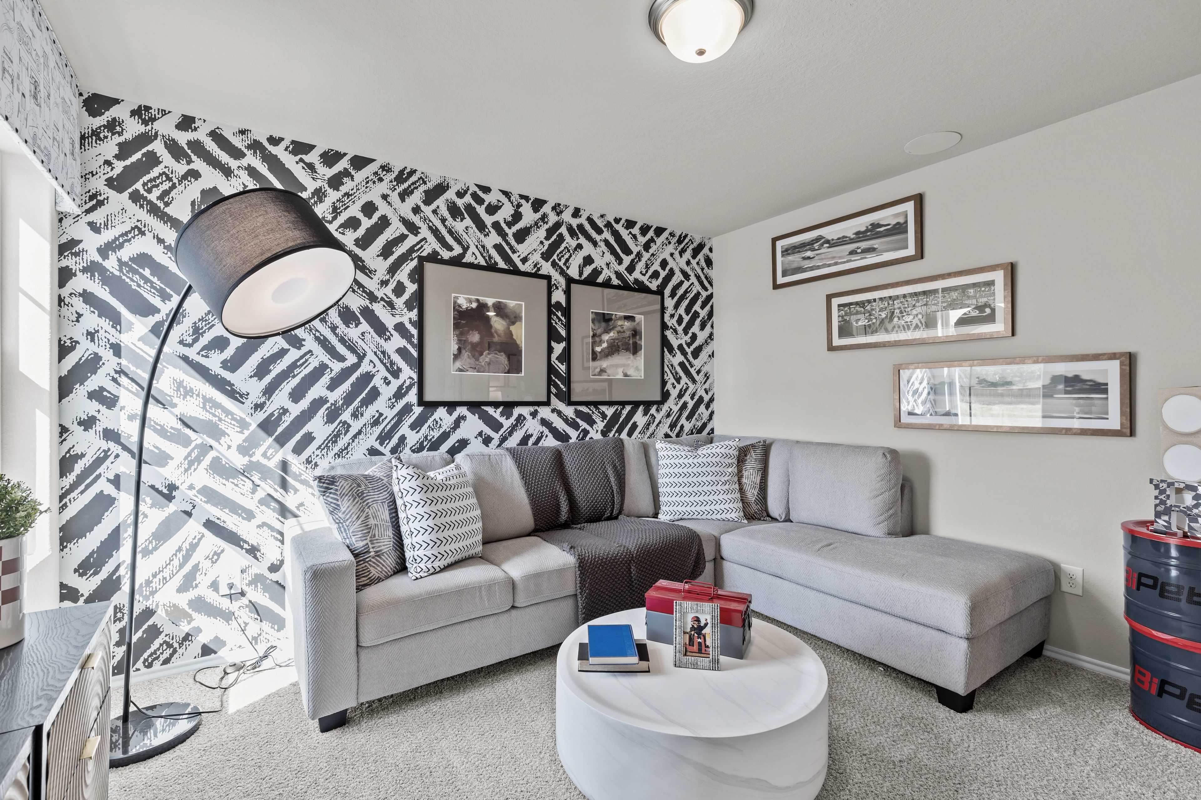 Cozy modern living room at Applewhite Meadows in San Antonio TX with gray L-shaped sectional, zigzag accent wall, and arc floor lamp