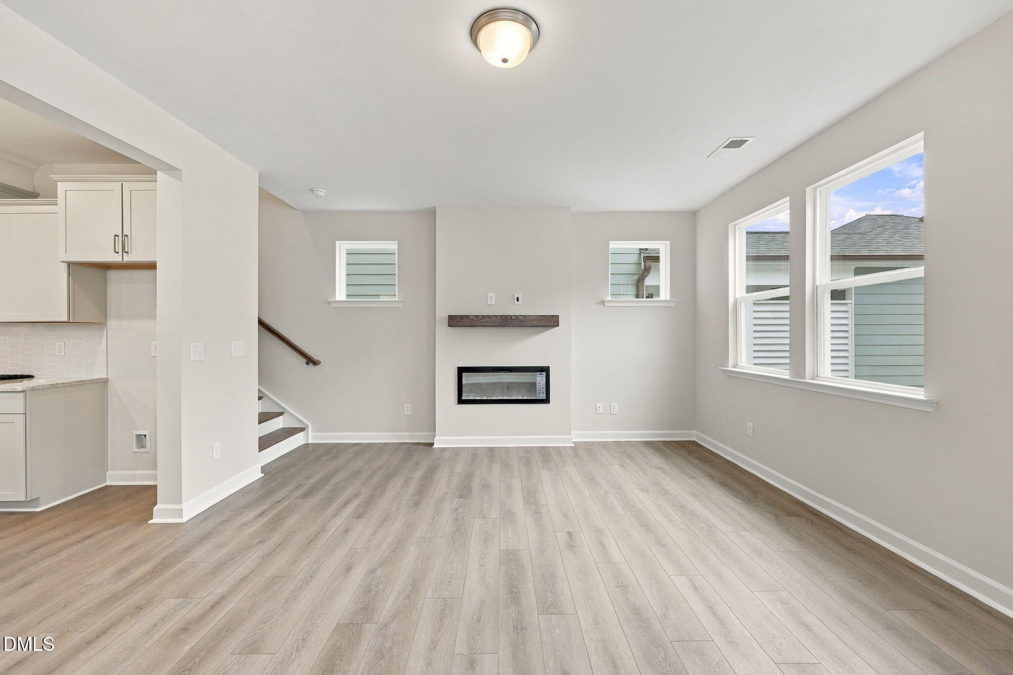 Bright open-concept living room with electric fireplace and luxury vinyl plank floors in Davidson Homes' The Alexander B, Knightdale NC