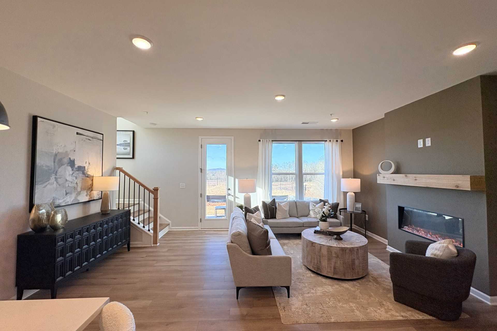 Open-concept living room in Hemingway Cumming GA by Davidson Homes with hardwood floors, modern gas fireplace, and plush sectional sofa
