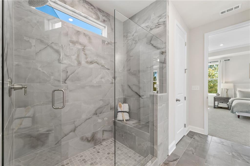 Elegant frameless glass shower with gray marble tiles, built-in bench in master bathroom of Davidson Homes The Danbury C, Buford GA