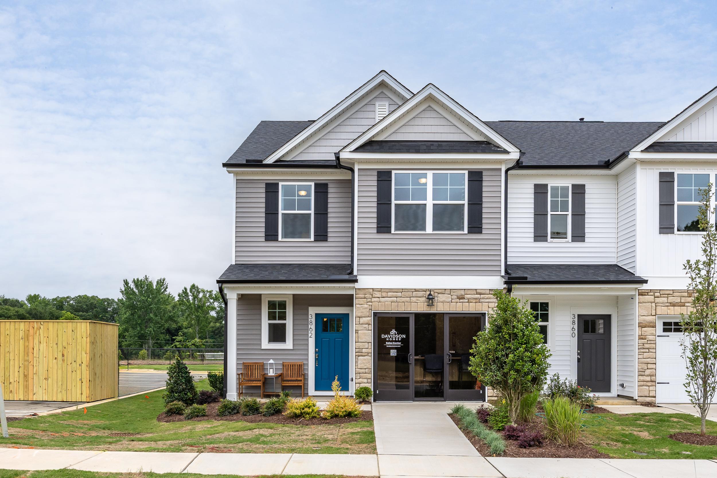 Modern duplex townhomes at Springvale in Fuquay-Varina NC by Davidson Homes featuring stone accents blue door and landscaped front yards