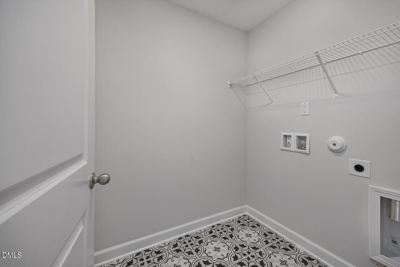 Laundry room with decorative tile flooring and wire shelving in The Adalynn B floor plan at Gregory Village, Lillington.