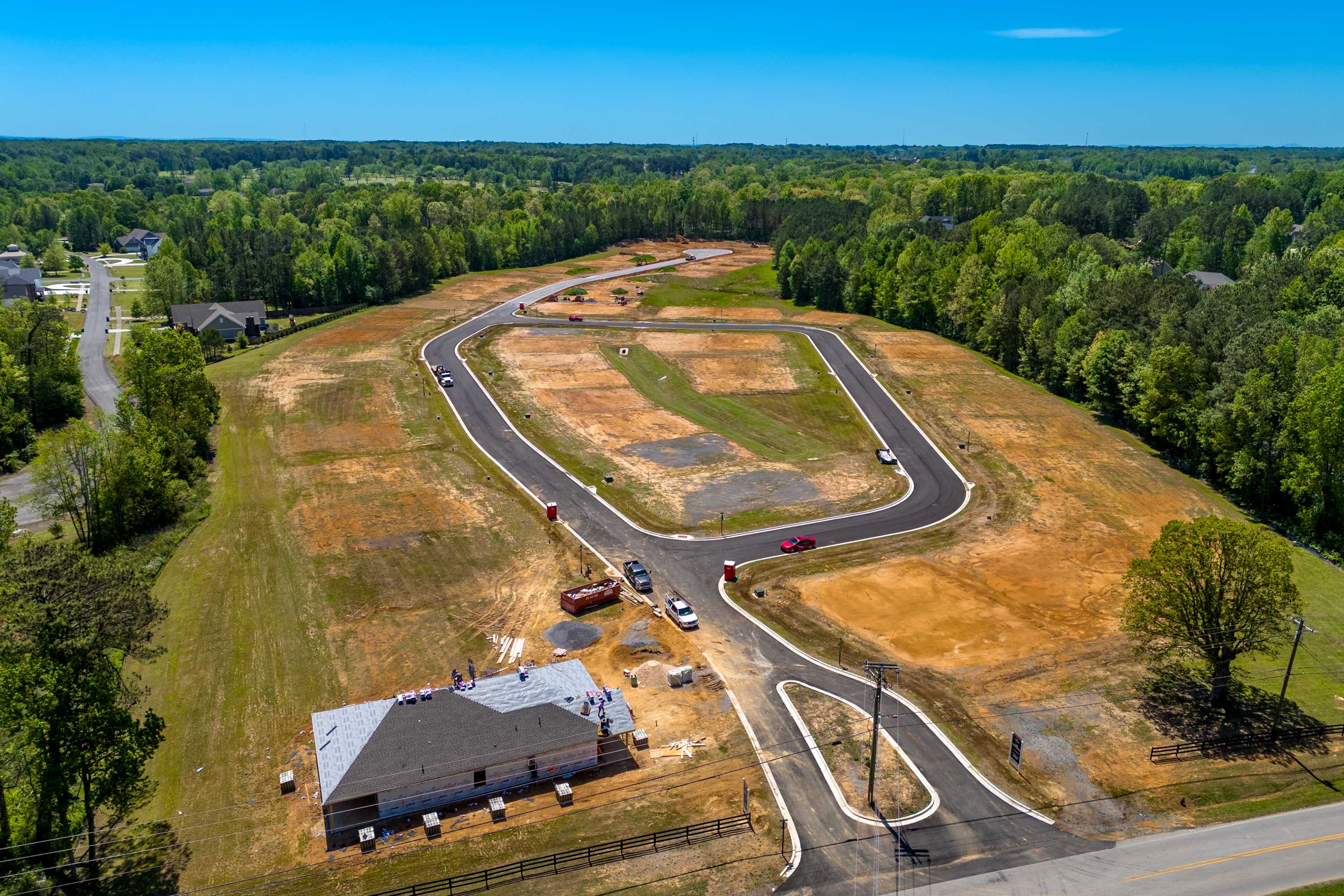 Aerial view of The Highlands neighborhood construction in Arab Alabama with dirt roads wooded surroundings and model home