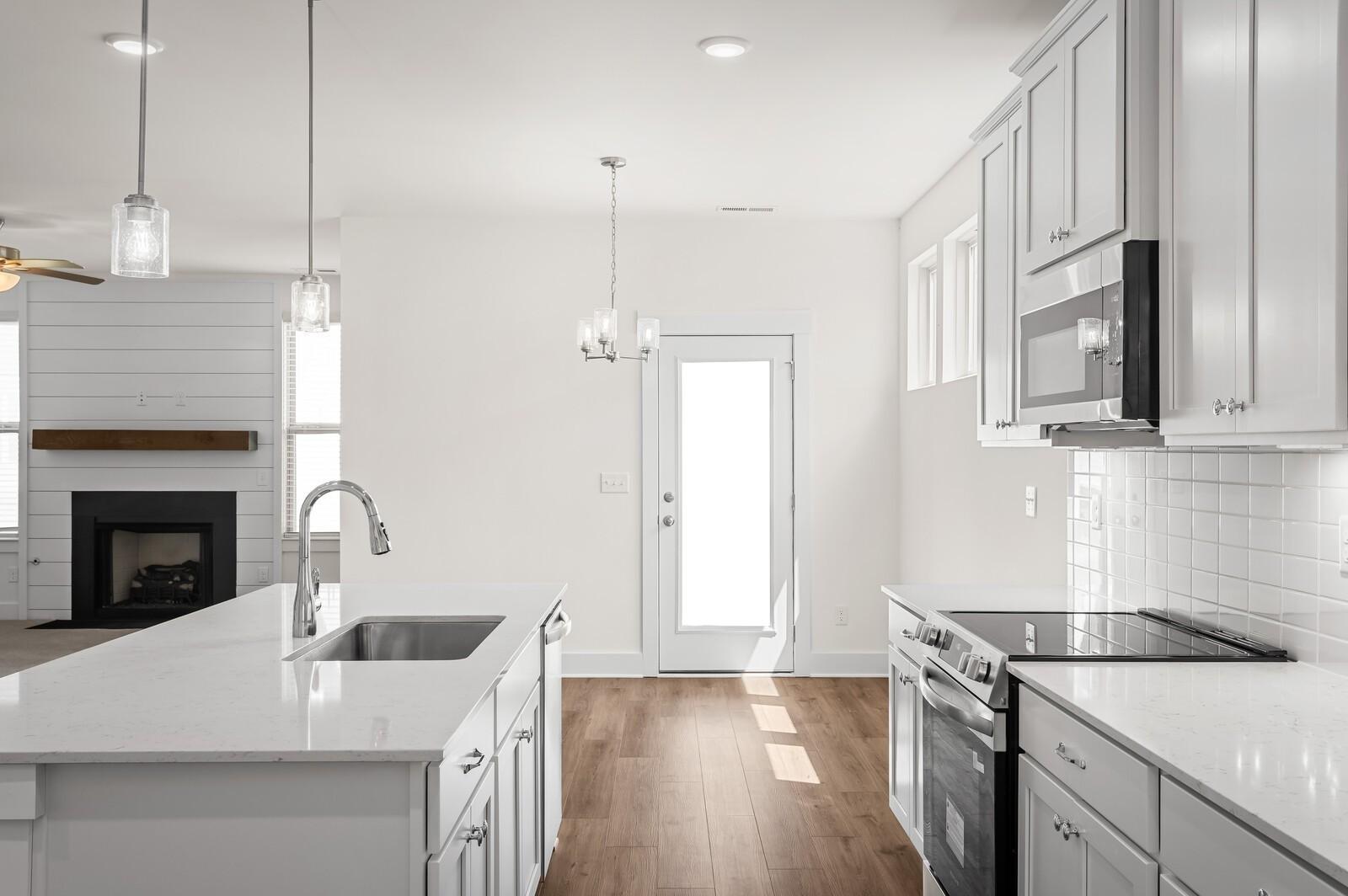 Modern kitchen with white cabinets, quartz countertops, and island in The Ash A plan at Woods Crossing, Gallatin, TN.