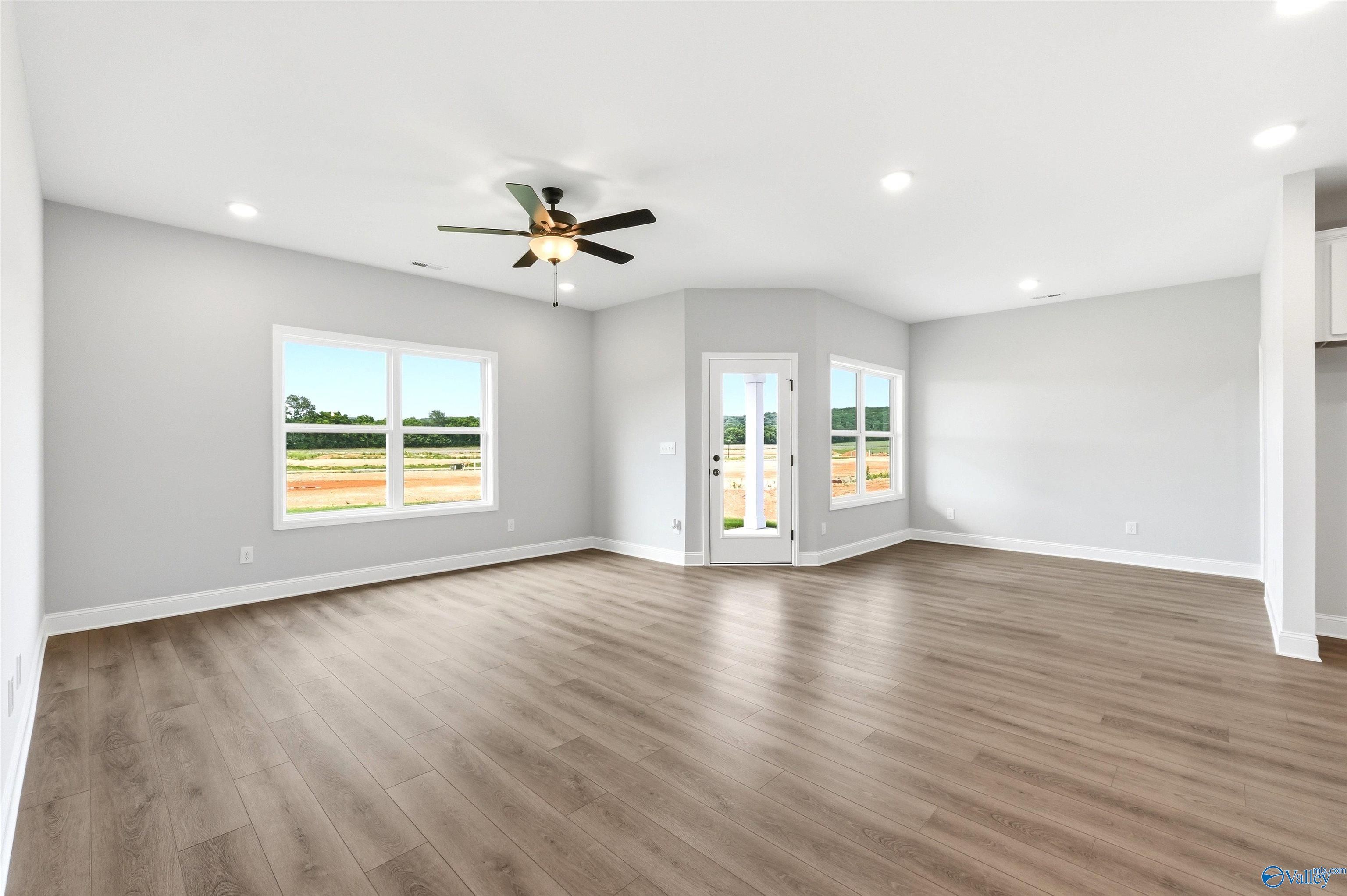 Spacious, light-filled living area with wood-style flooring in The Daphne F floor plan at Berry Cove, New Market, Alabama.